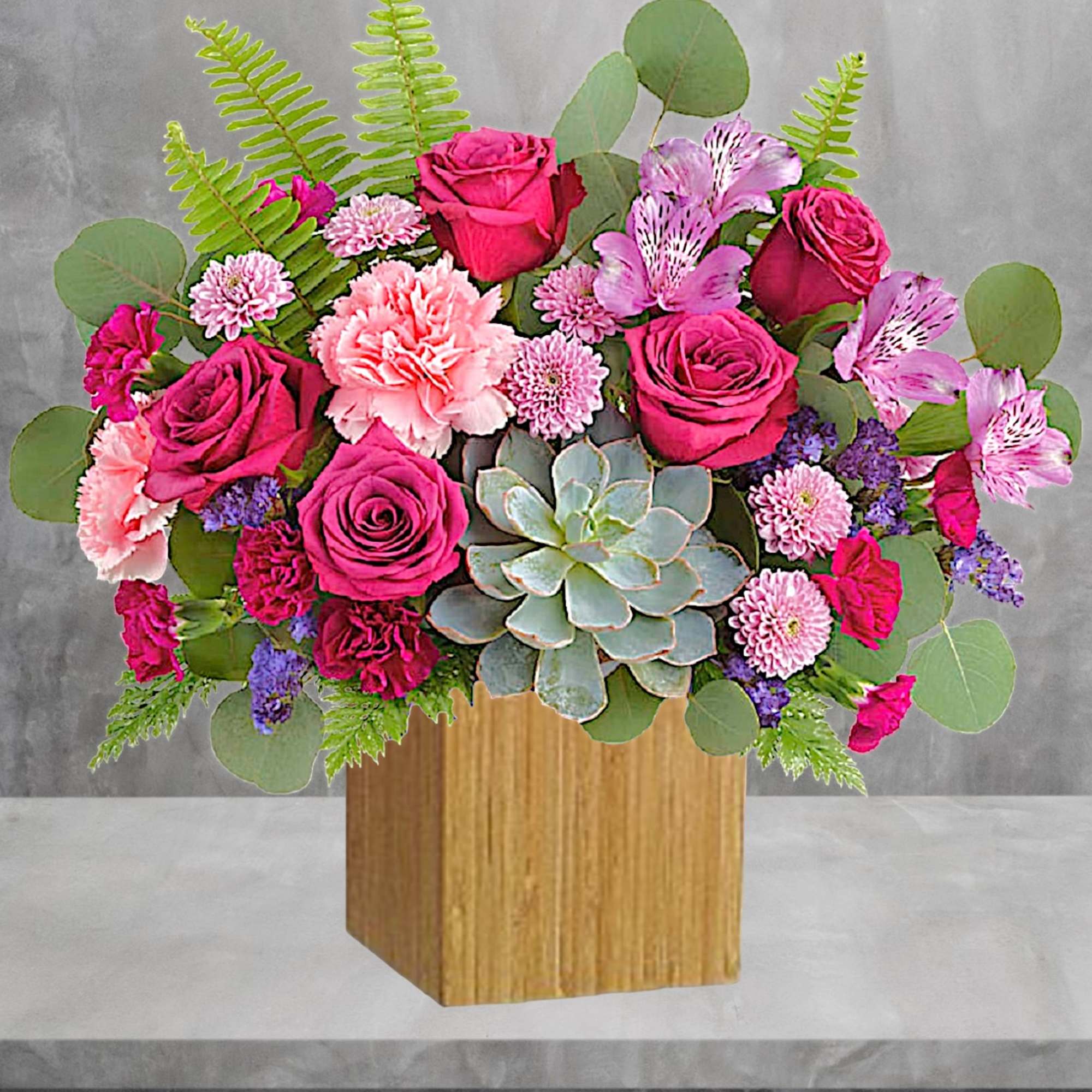 Pink roses and carnations with a succulent in a wooden box