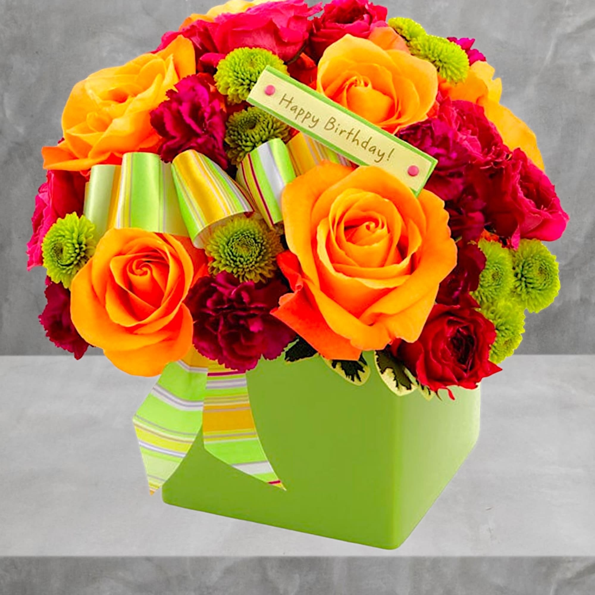 Bright bouquet of orange and red roses with green button mums in a lime box