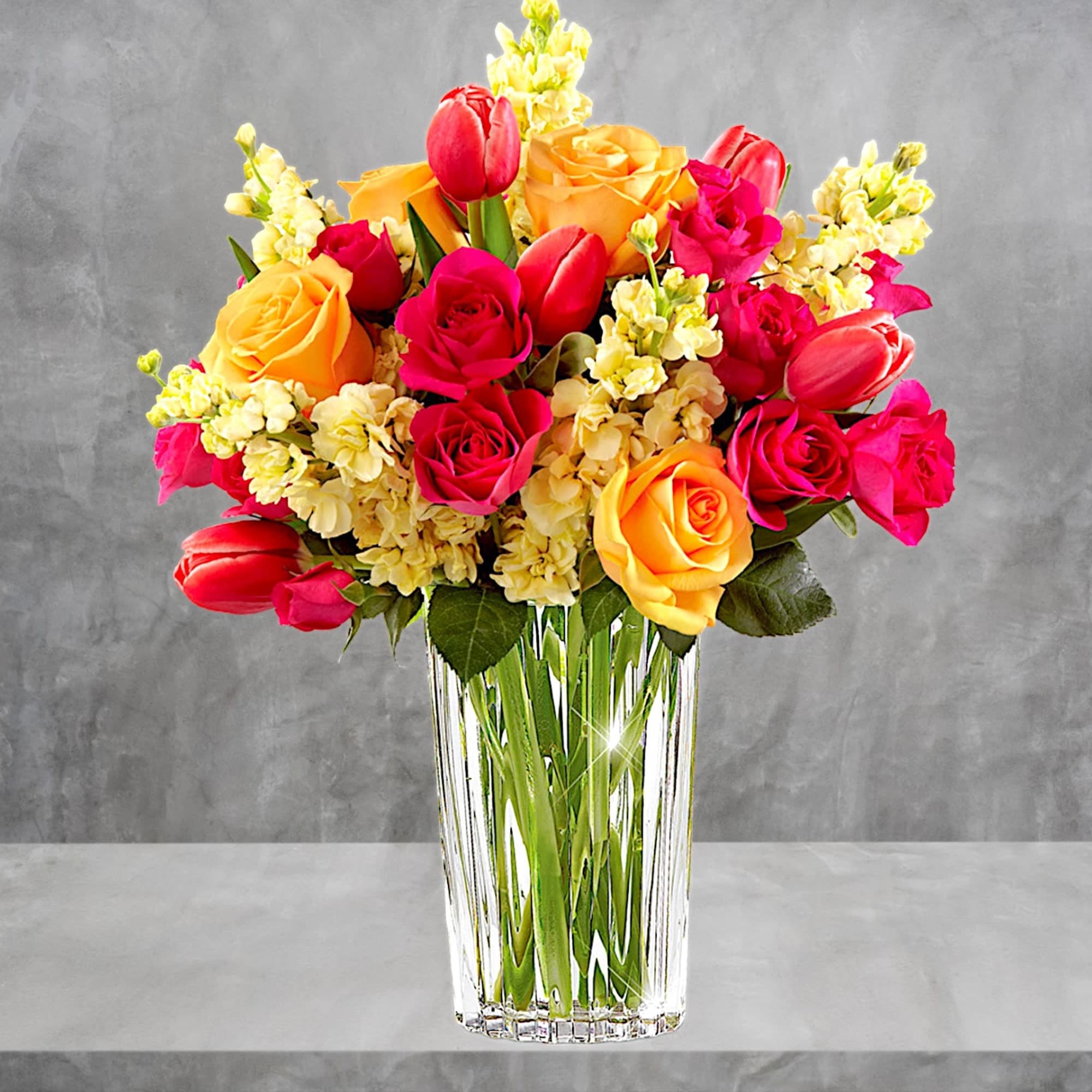 Bouquet of pink and yellow roses with tulips in a clear glass vase, photo 2 of 4