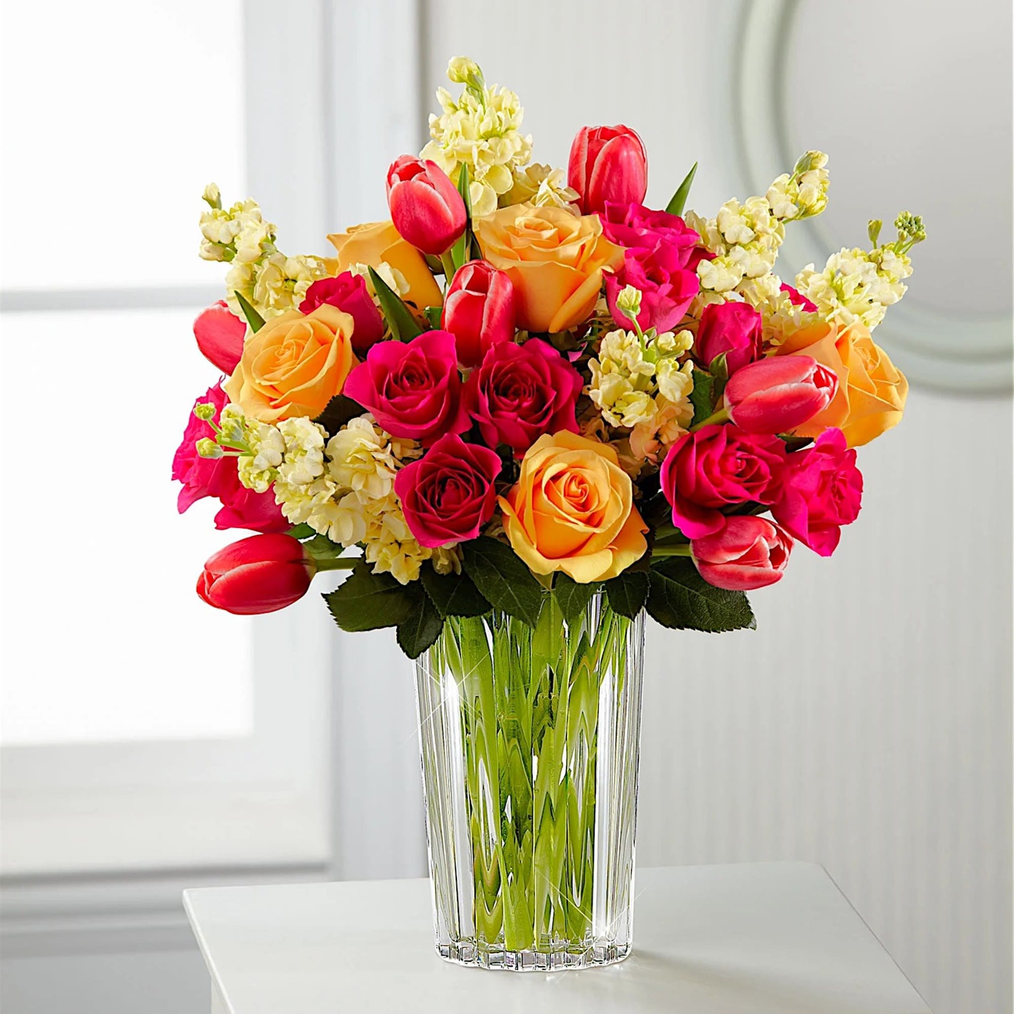 Bouquet of roses and tulips in a clear glass vase