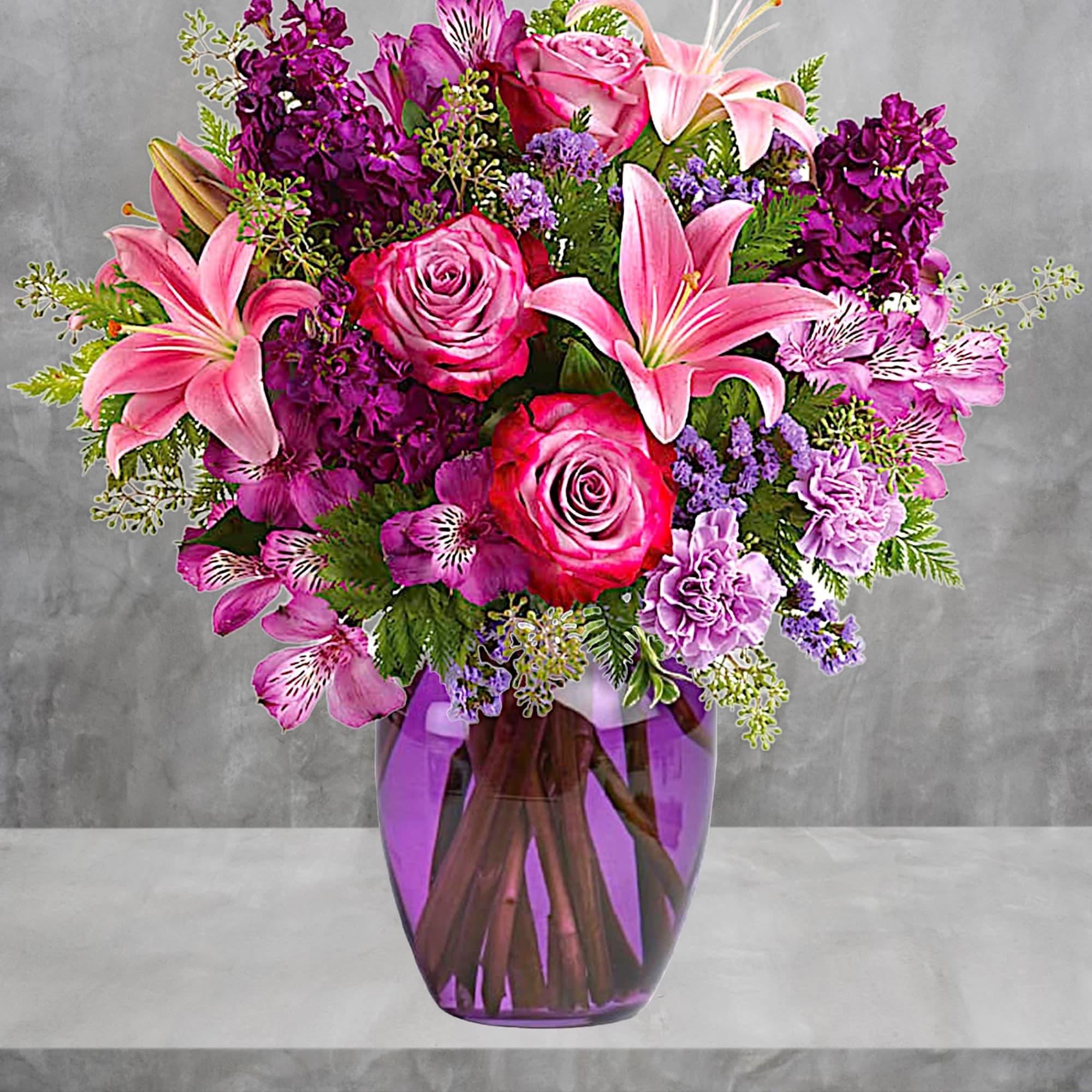 Pink lilies and roses in a purple glass vase