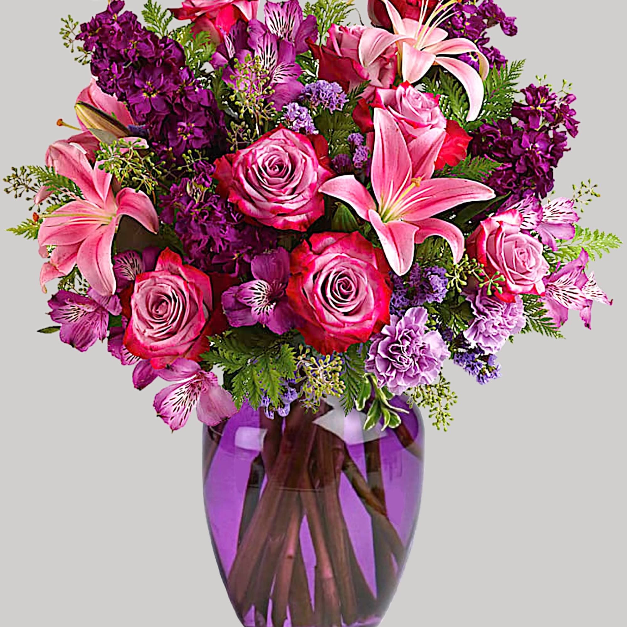 Pink roses and lilies in a purple glass vase