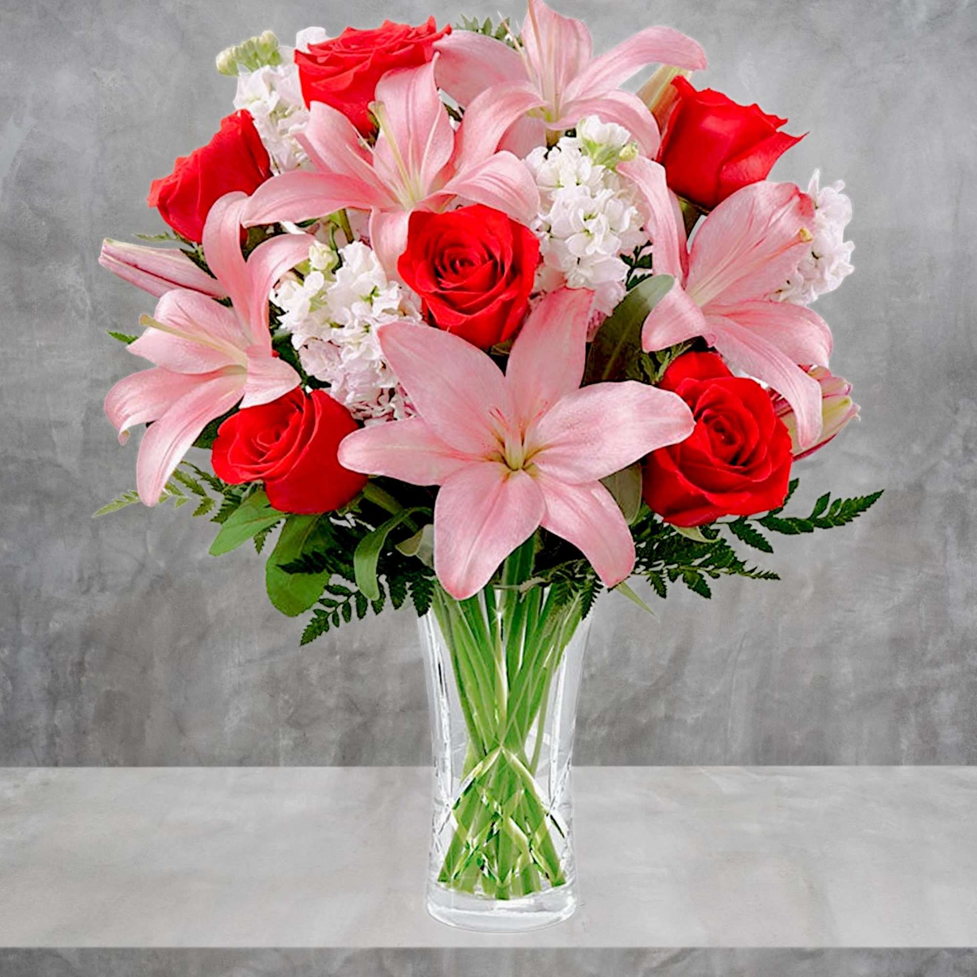 Pink lilies and red roses arranged in a clear glass vase, photo 2 of 4