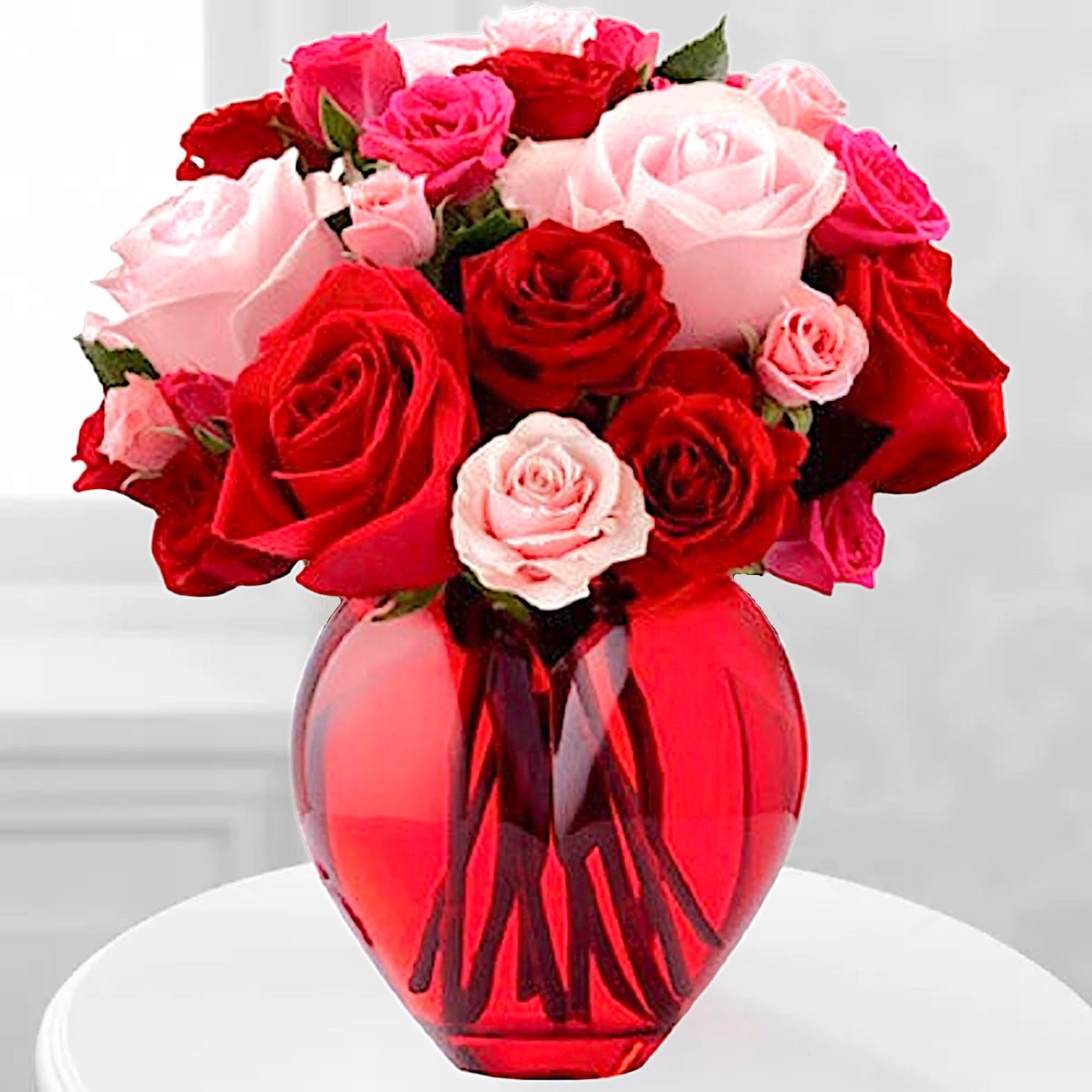 Red and pink roses arranged in a red glass vase, photo 2 of 5
