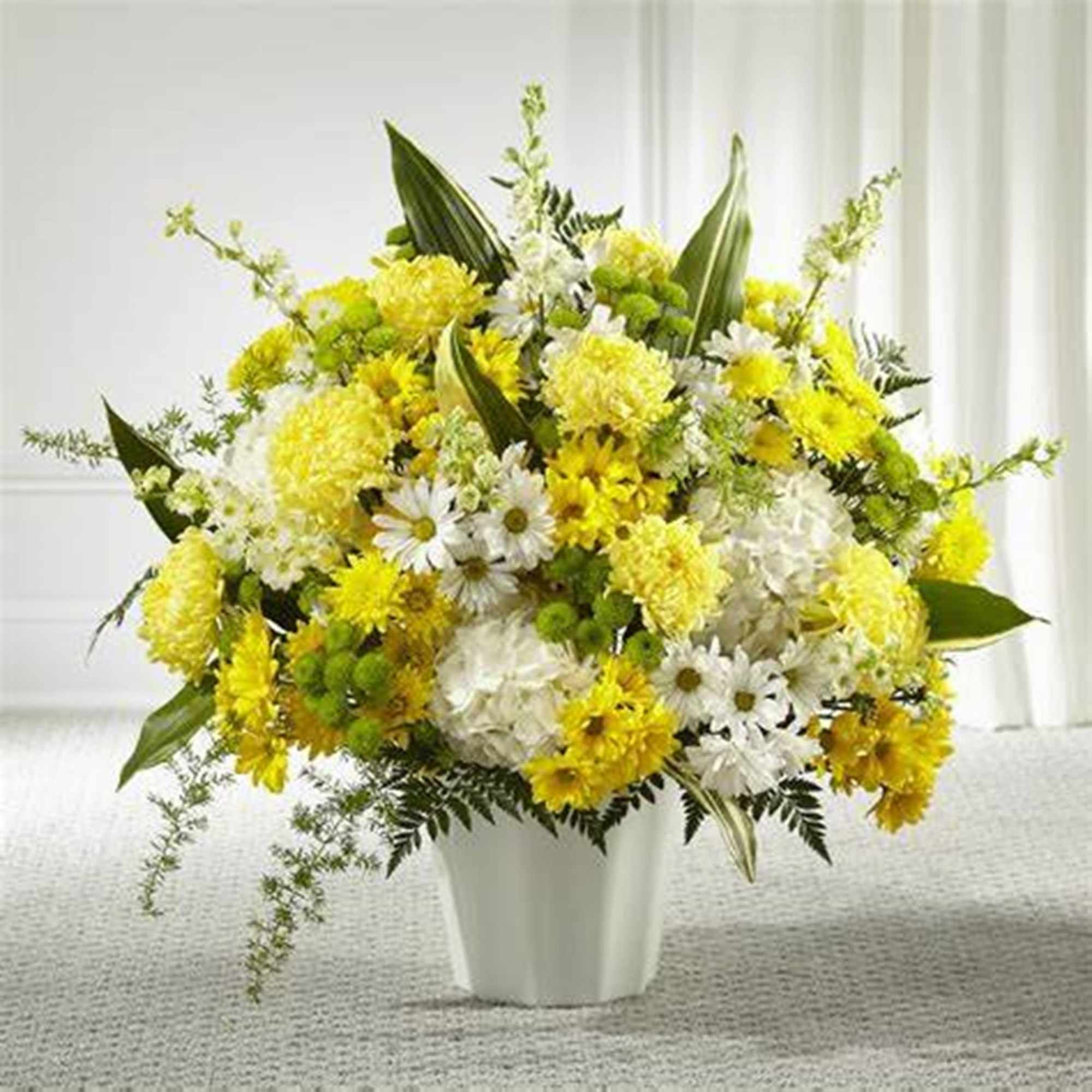 Yellow and white flower arrangement in a white vase