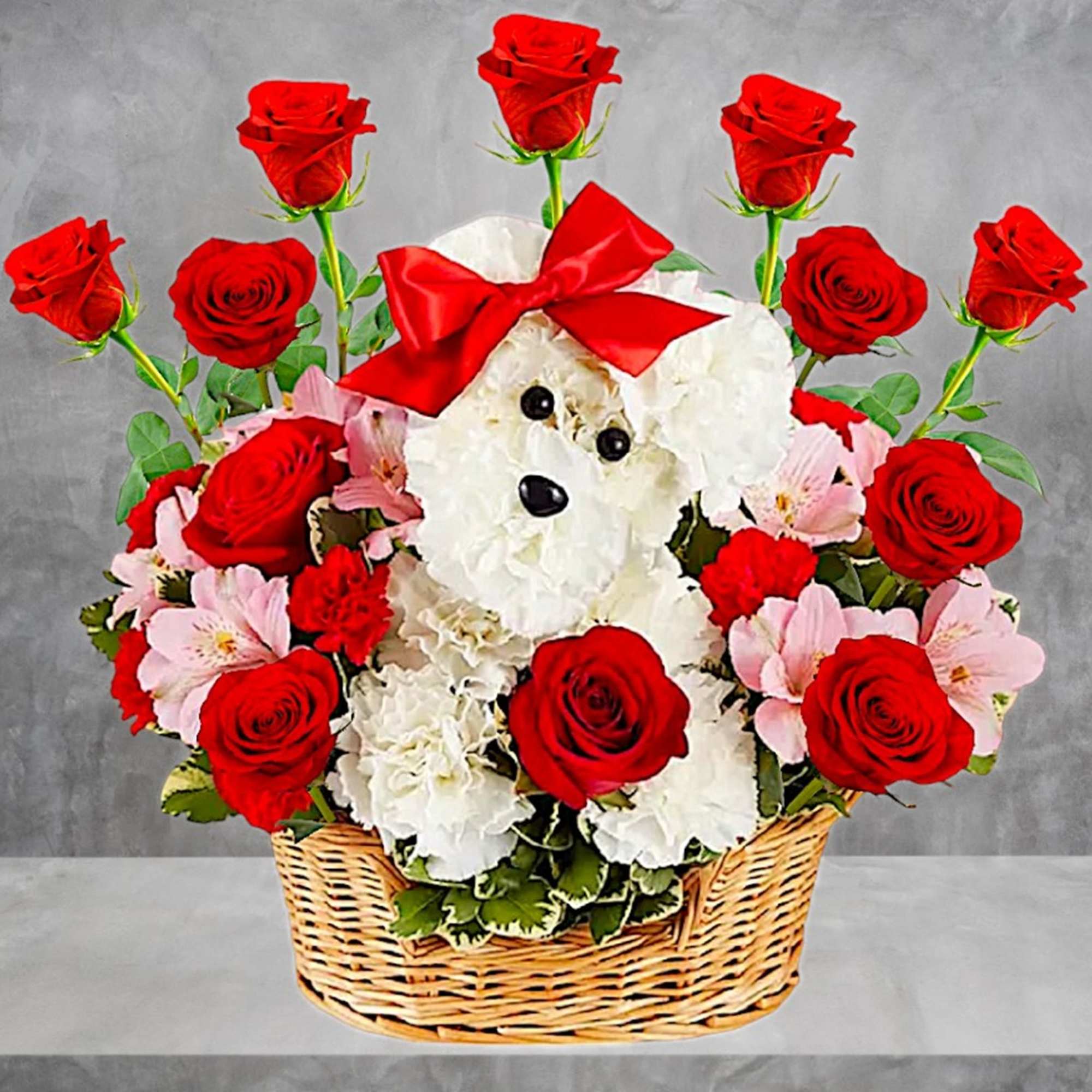 Red roses and white flowers arranged around a teddy bear in a basket