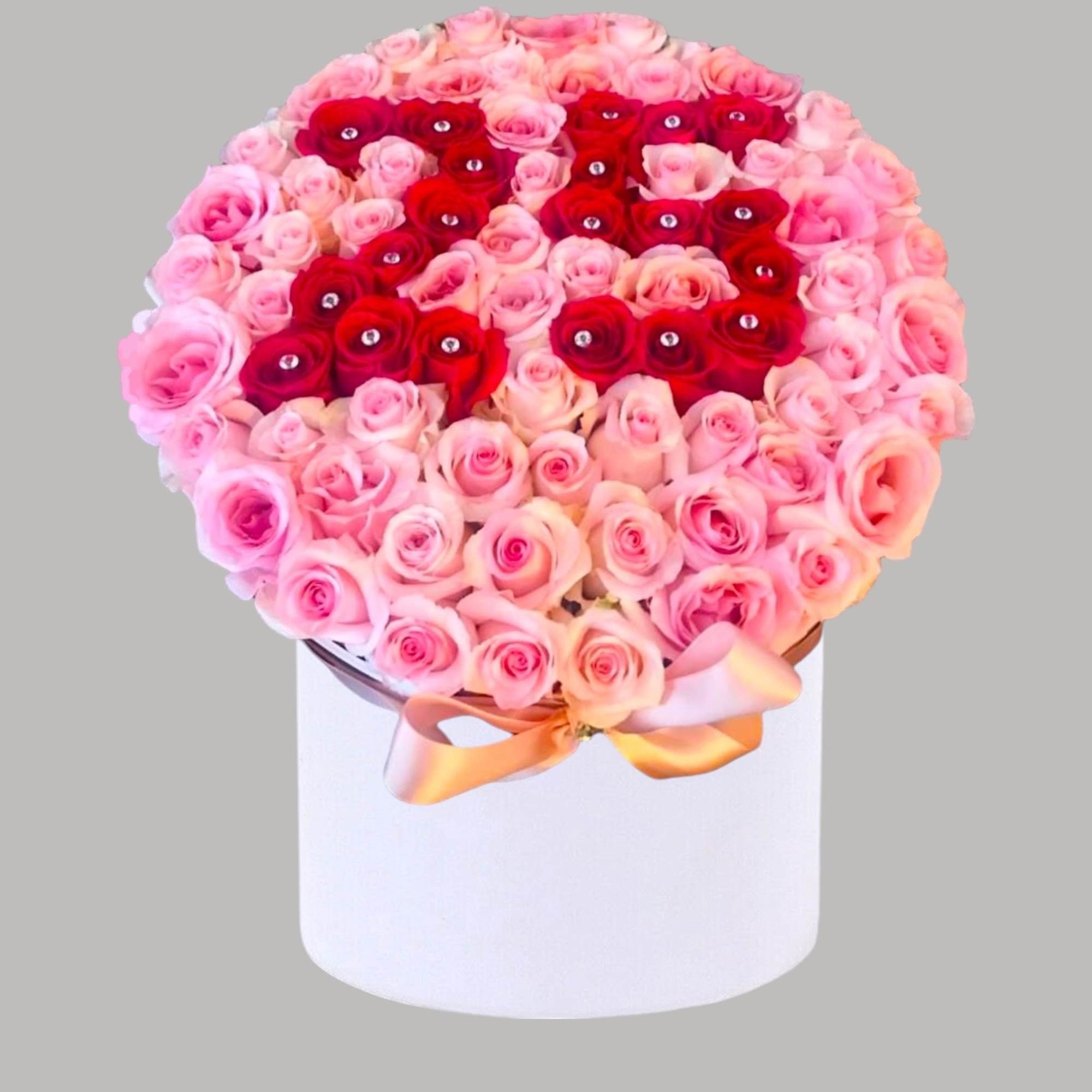 Round bouquet of pink and red roses in a white box with a ribbon