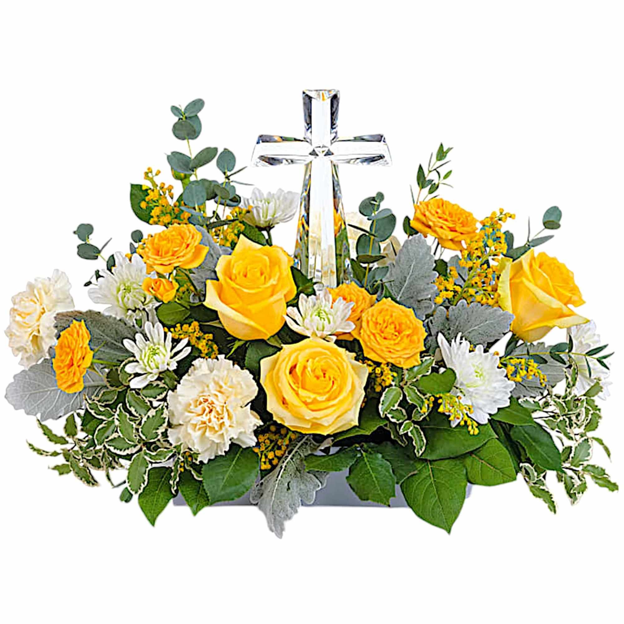 Yellow roses and white flowers arranged around a clear glass cross