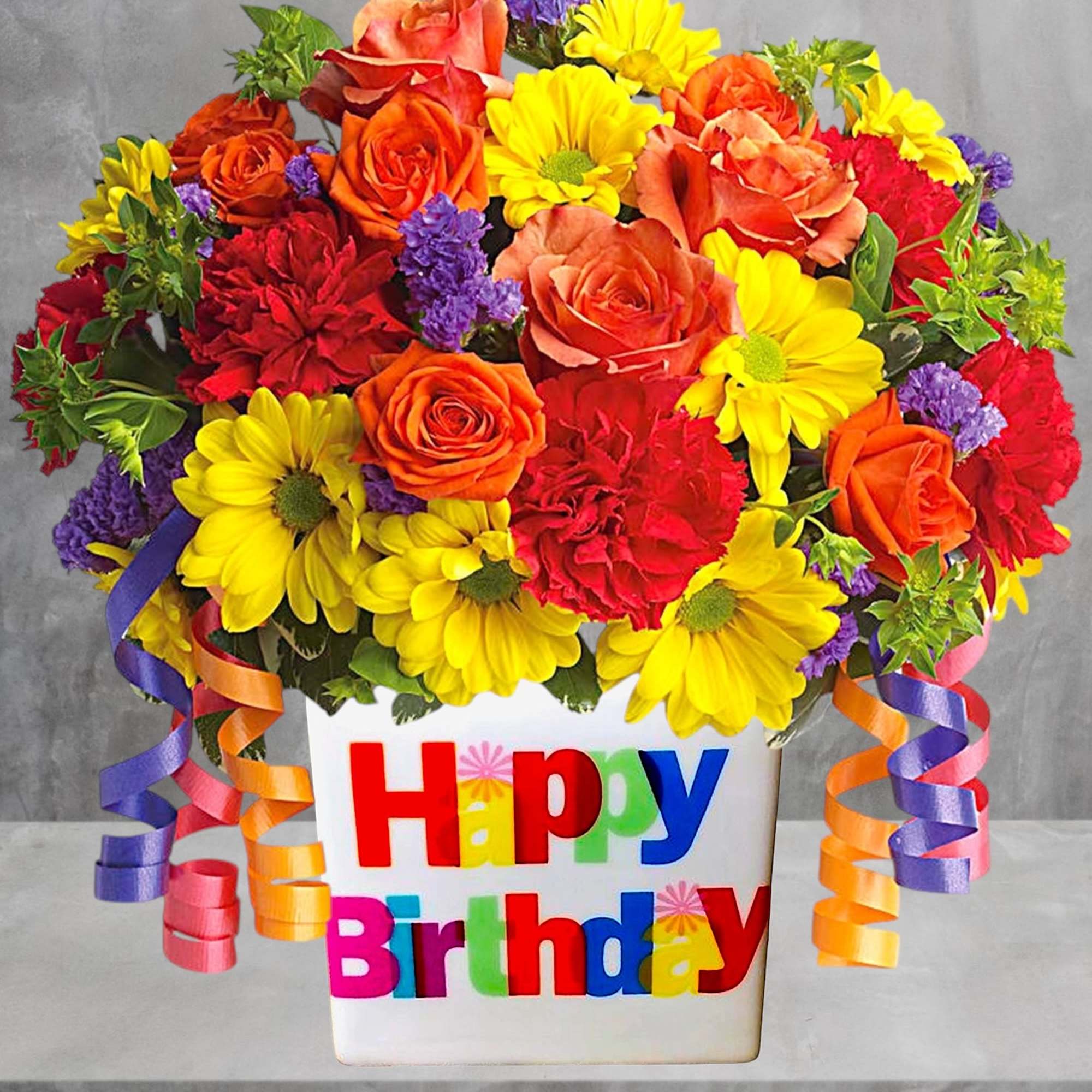 Colorful birthday flower arrangement in a white vase with ribbon curls