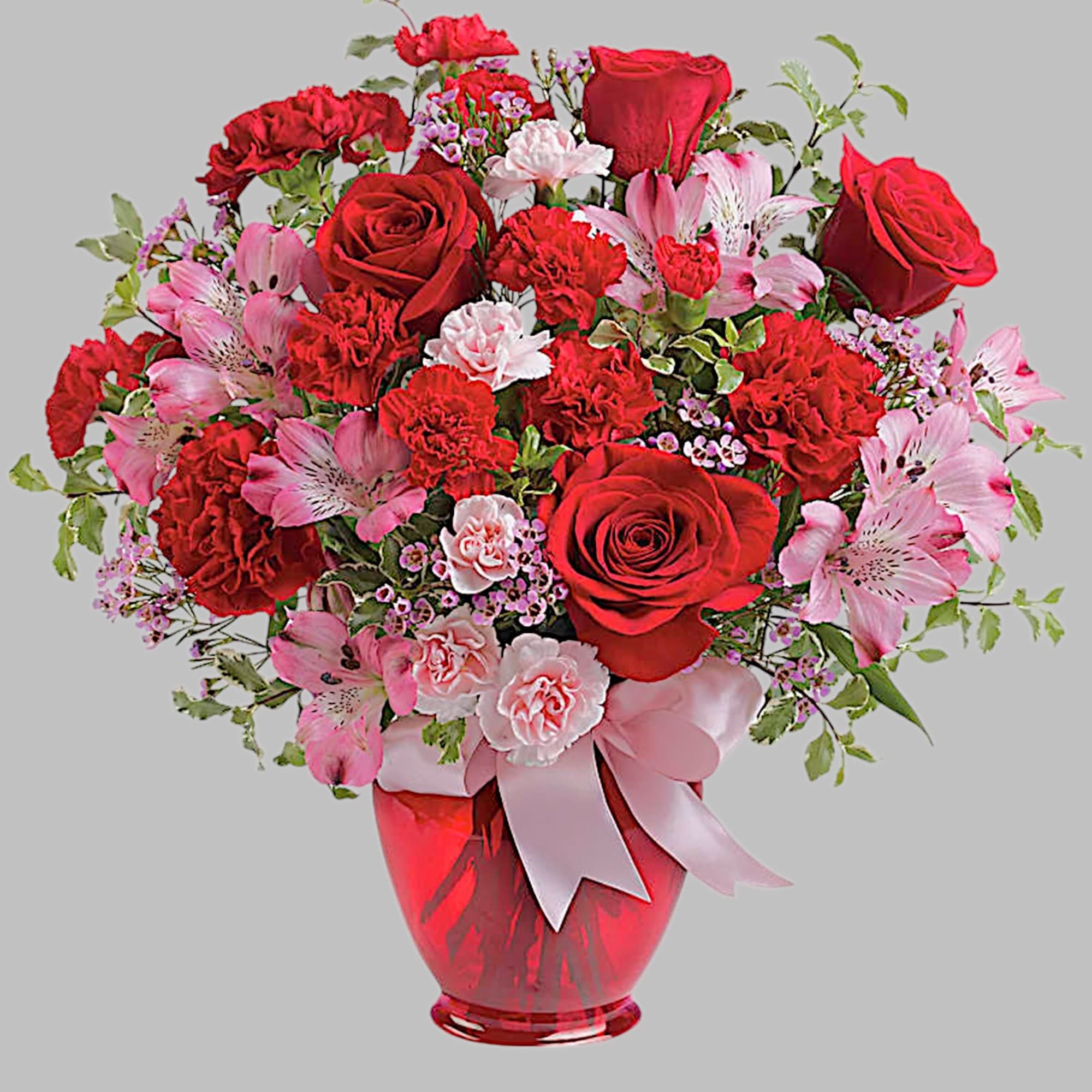Red and pink bouquet of roses and carnations in a red glass vase