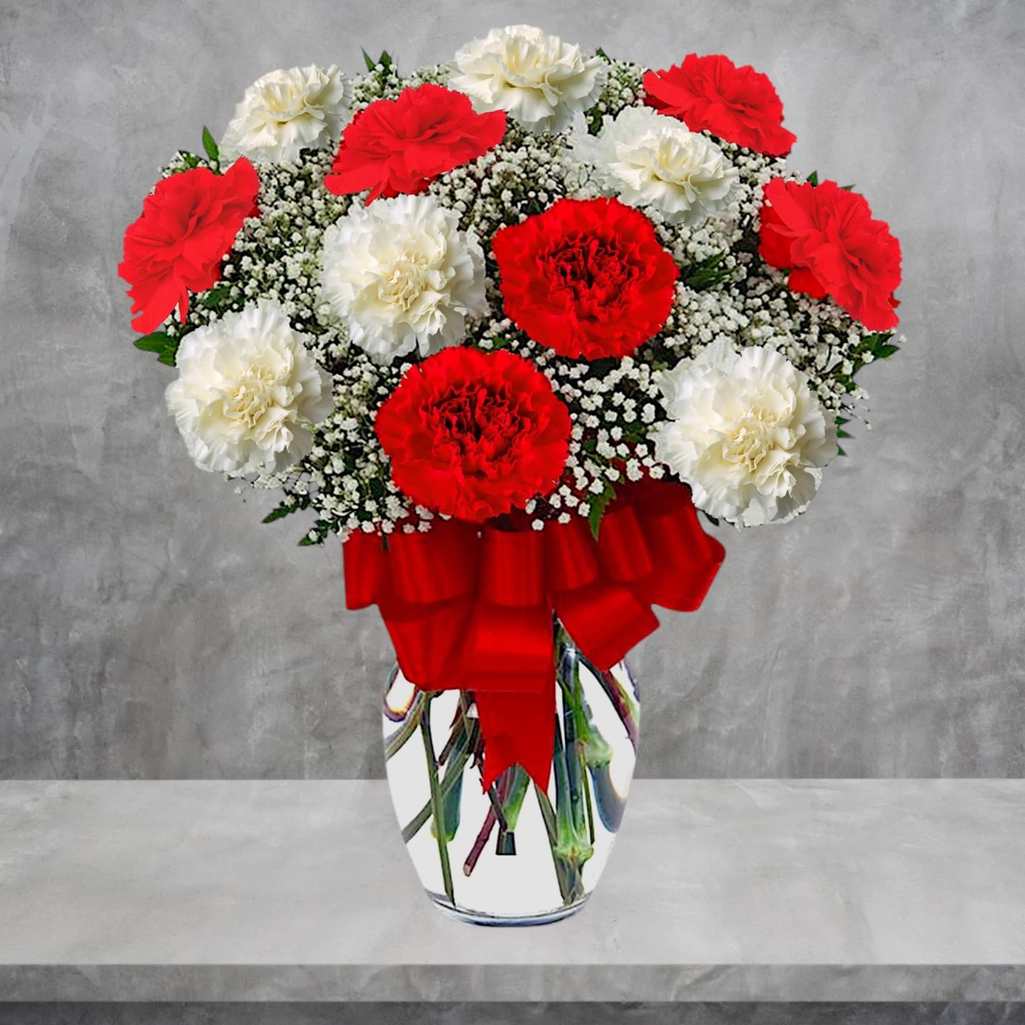 Red and white carnations in a glass vase with a red ribbon, photo 2 of 4
