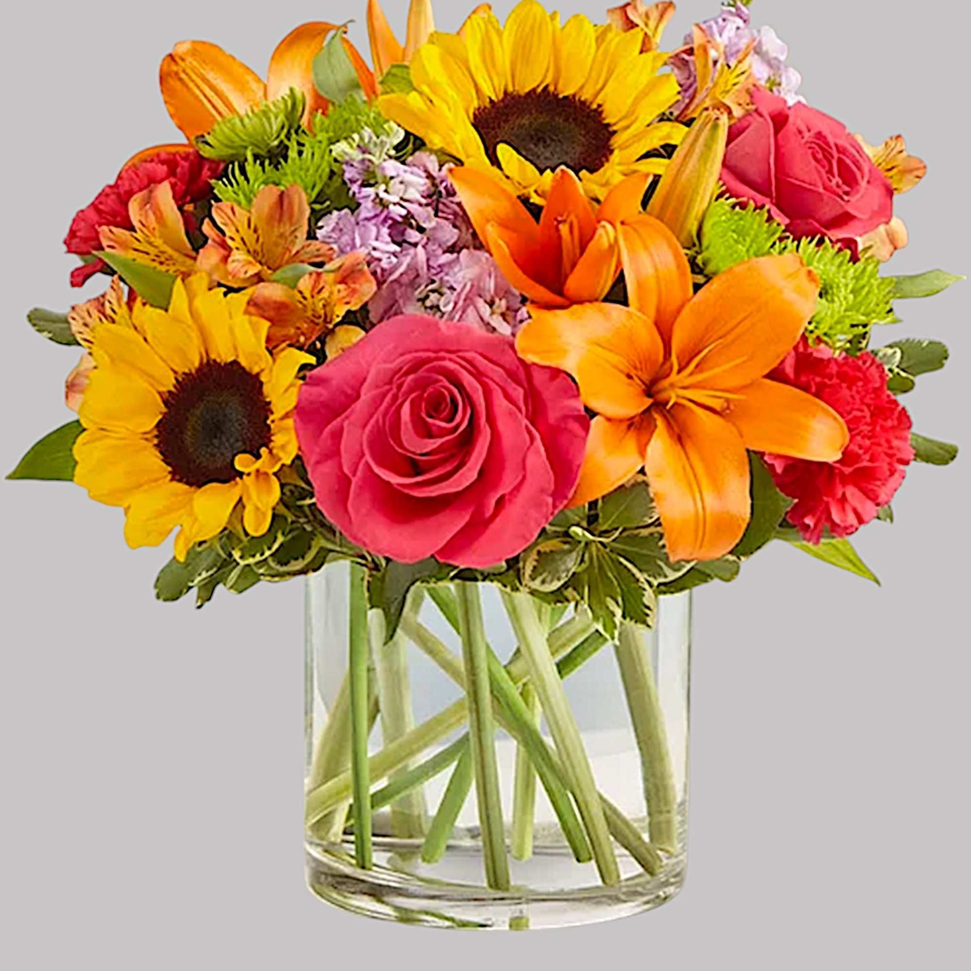 Bright mixed bouquet with sunflowers, roses, lilies, and alstroemeria in a glass vase