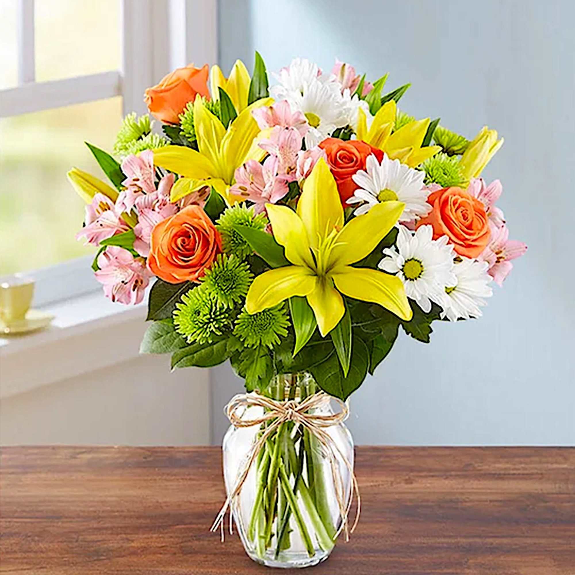 Bouquet of yellow lilies, orange roses, and white daisies in a glass vase, photo 2 of 5