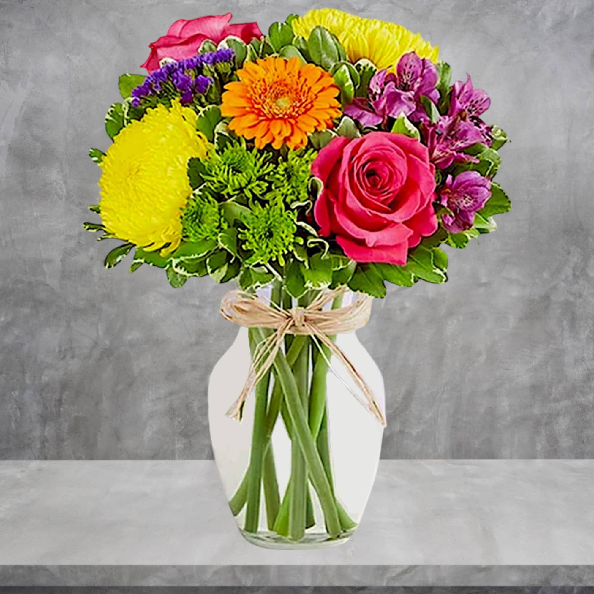 Mixed bouquet of bright flowers in a white vase with a raffia bow
