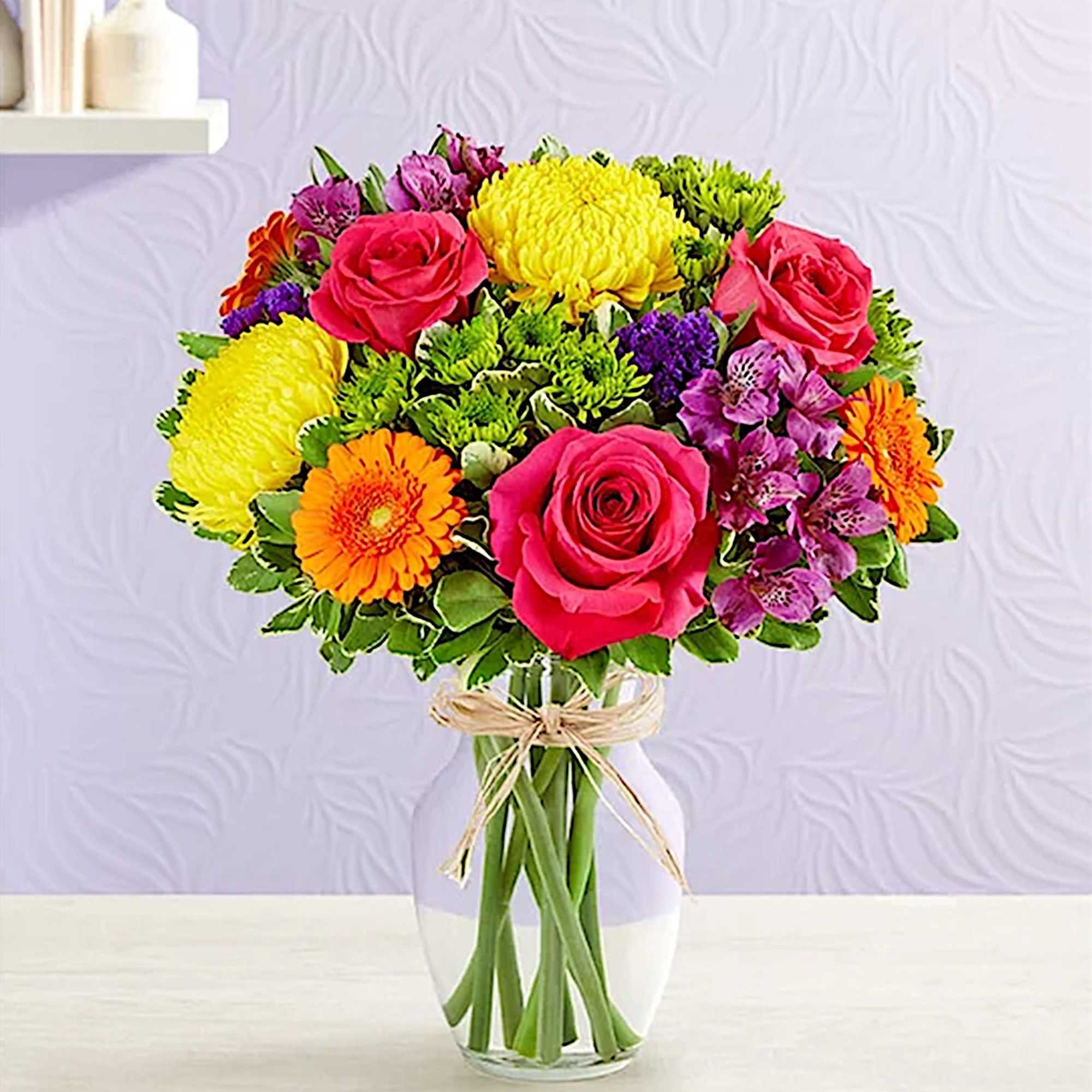 Mixed bouquet of roses, chrysanthemums, and gerbera daisies in a glass vase
