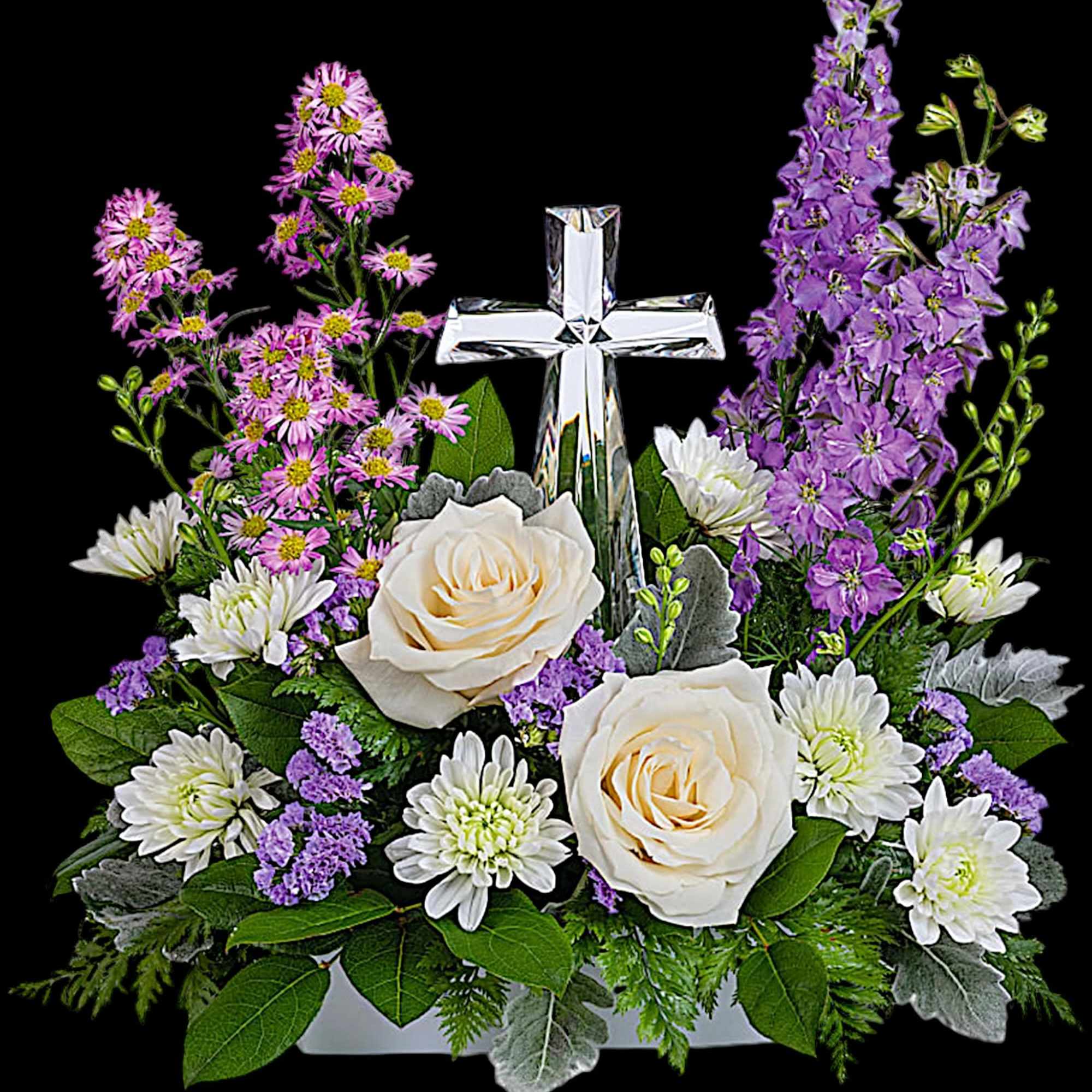 White roses and purple flowers arranged around a clear cross centerpiece