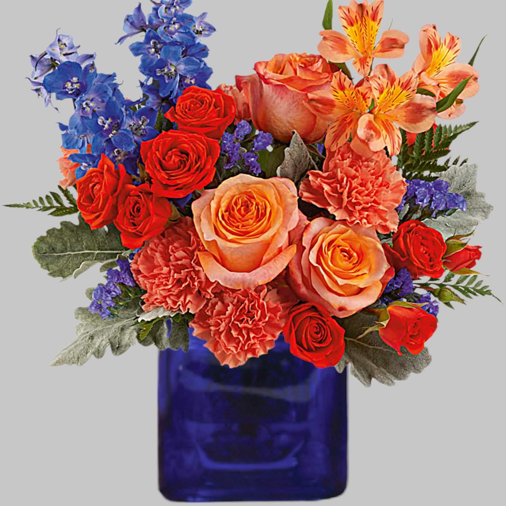 Mixed bouquet of roses, carnations, and blue flowers in a blue vase
