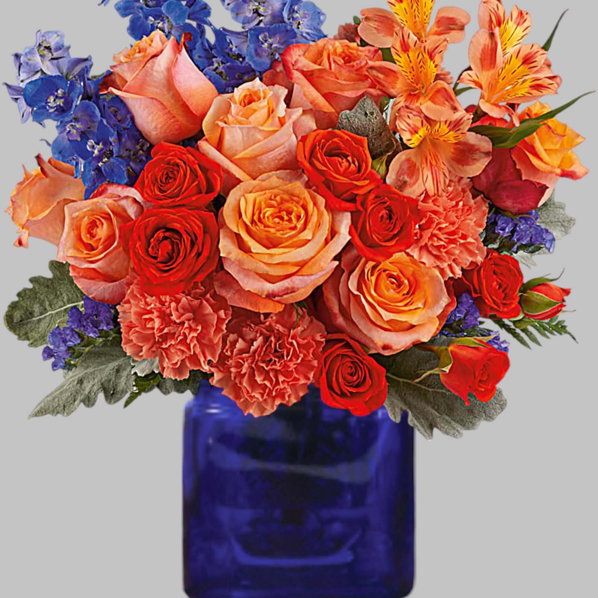 Mixed bouquet of roses, carnations, and blue flowers in a cobalt vase