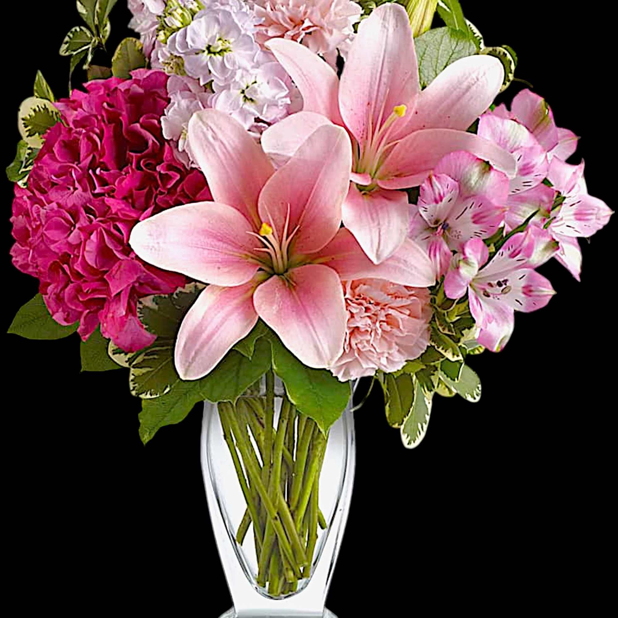 Pink lilies and mixed pink flowers in a clear glass vase