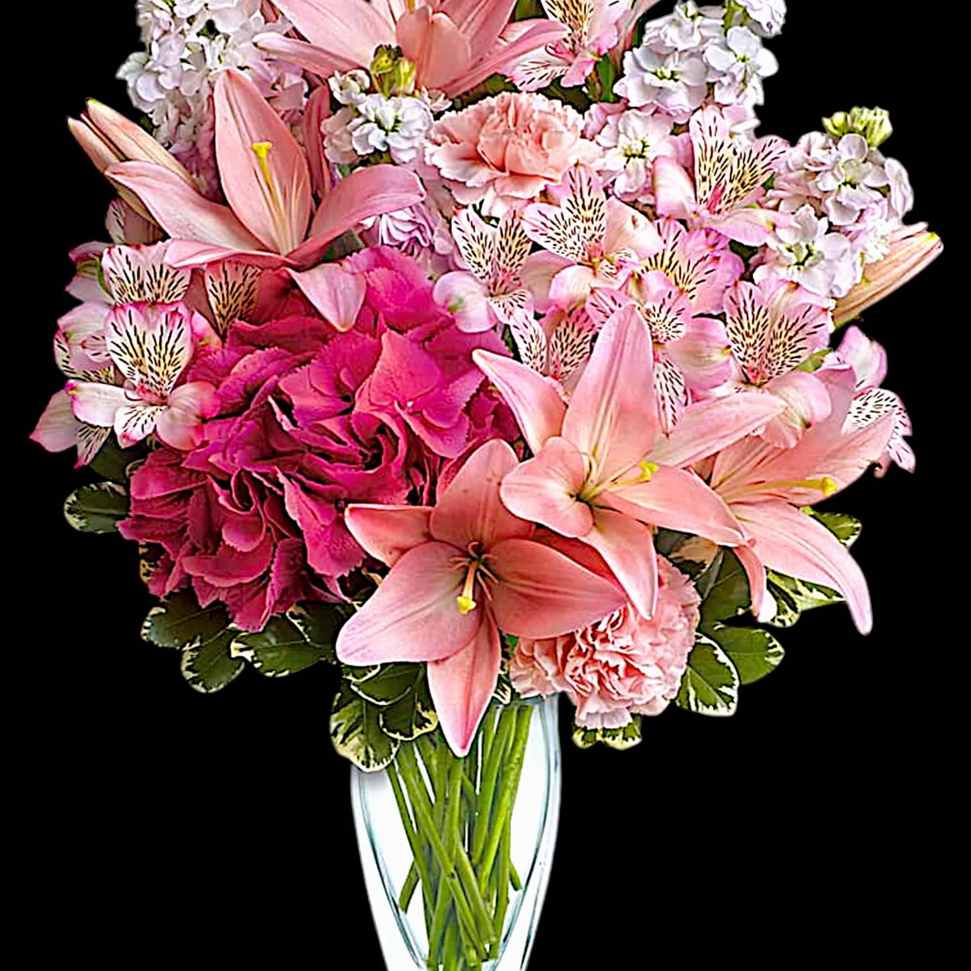 Pink lilies and carnations arranged in a clear glass vase