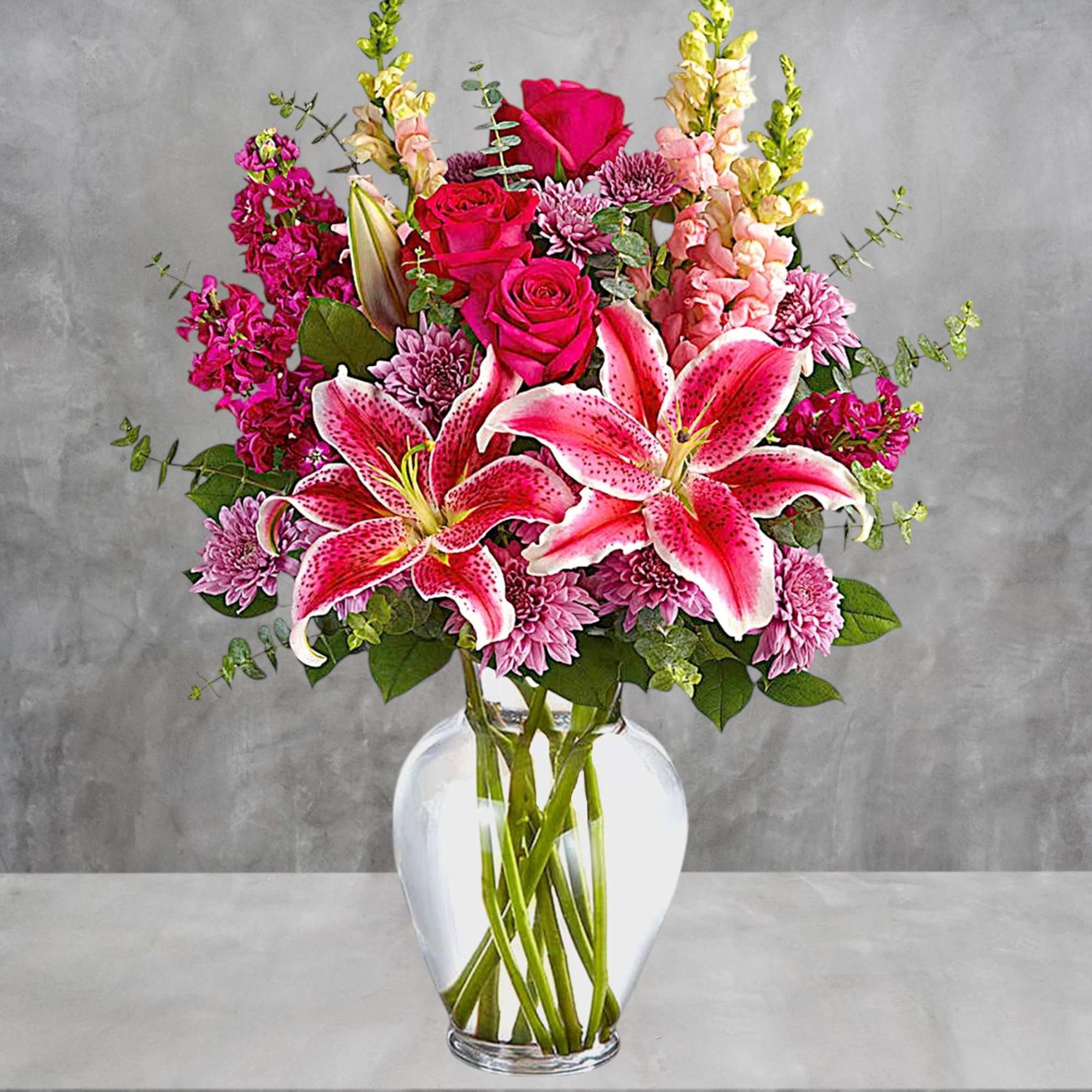 Pink lilies and roses arranged in a clear glass vase