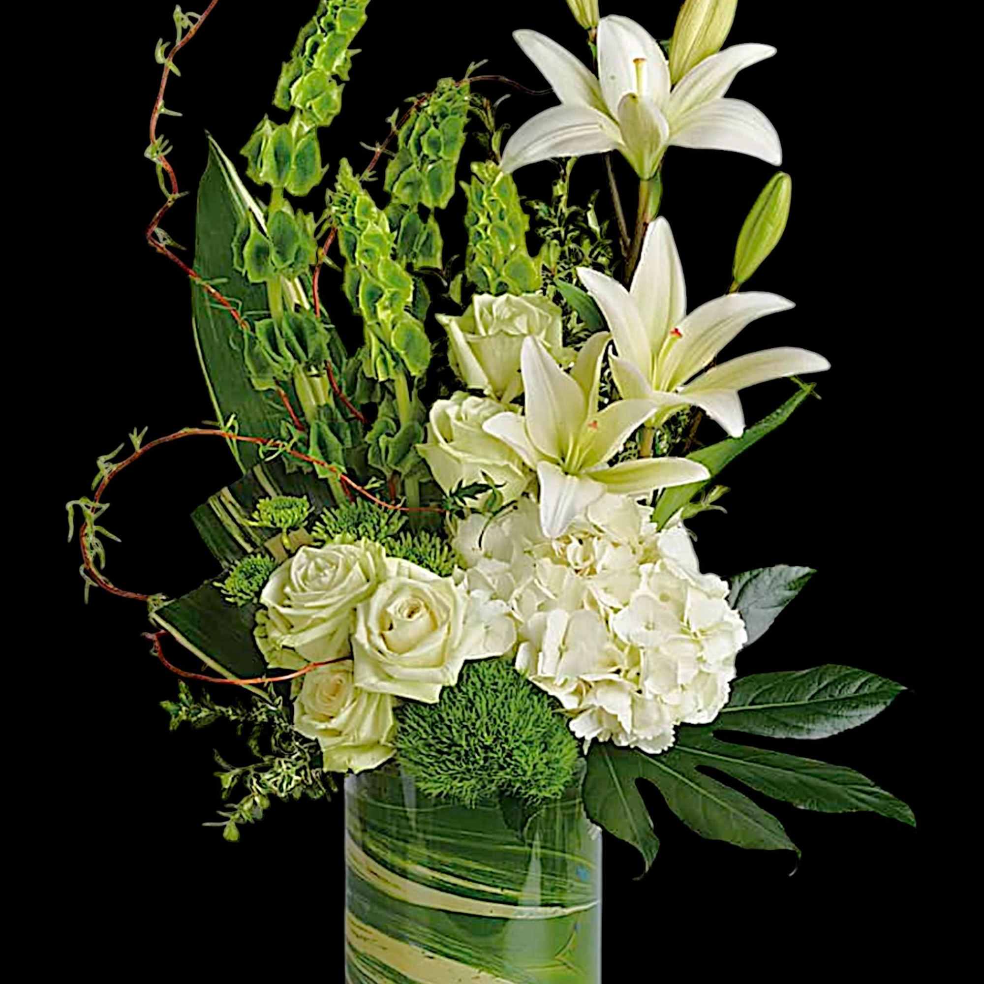 White lilies and roses arranged in a glass vase with green accents
