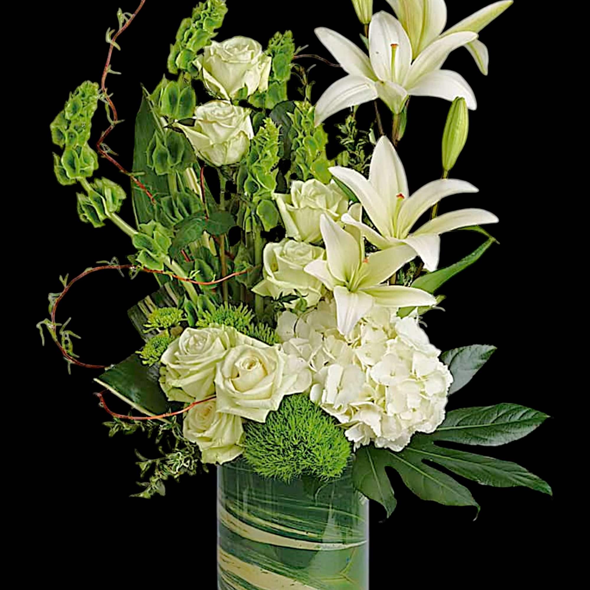 White lilies and roses in a glass vase with green accents