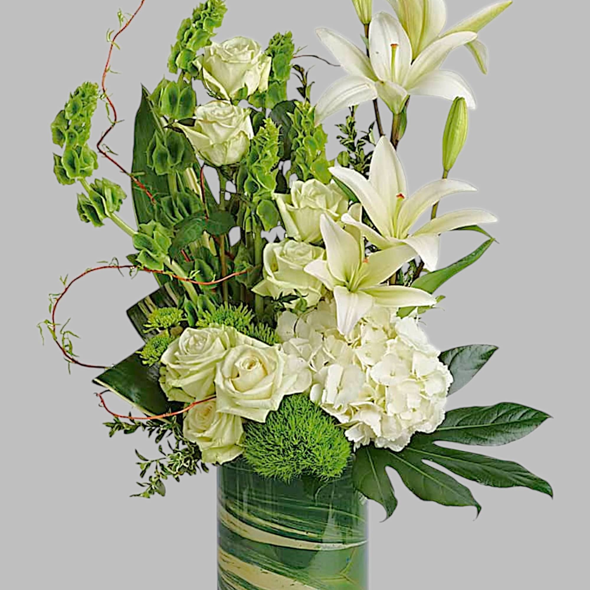 White lilies and roses arranged in a tall glass vase