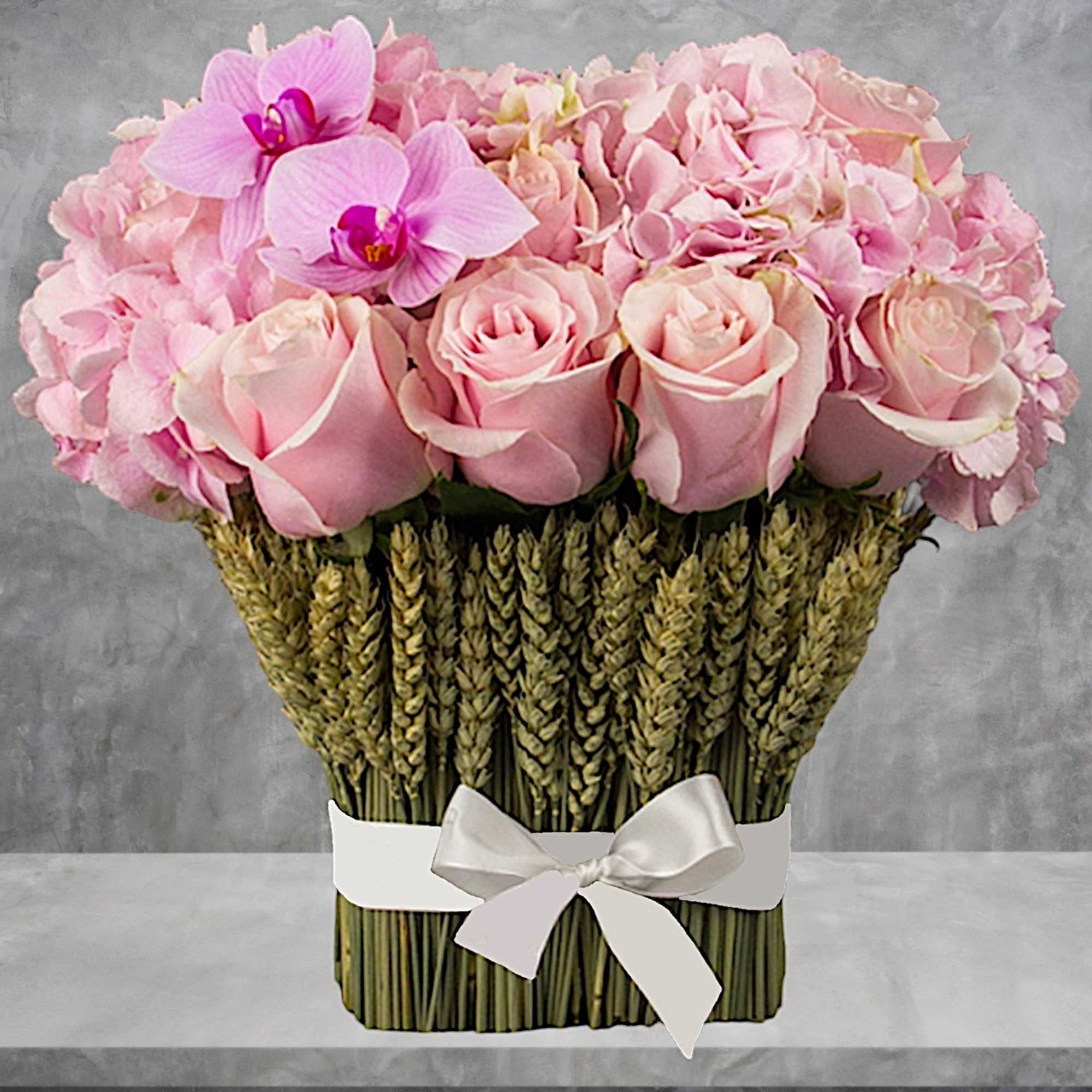 Pink roses and orchids arranged in a woven basket with a white ribbon, photo 3 of 11