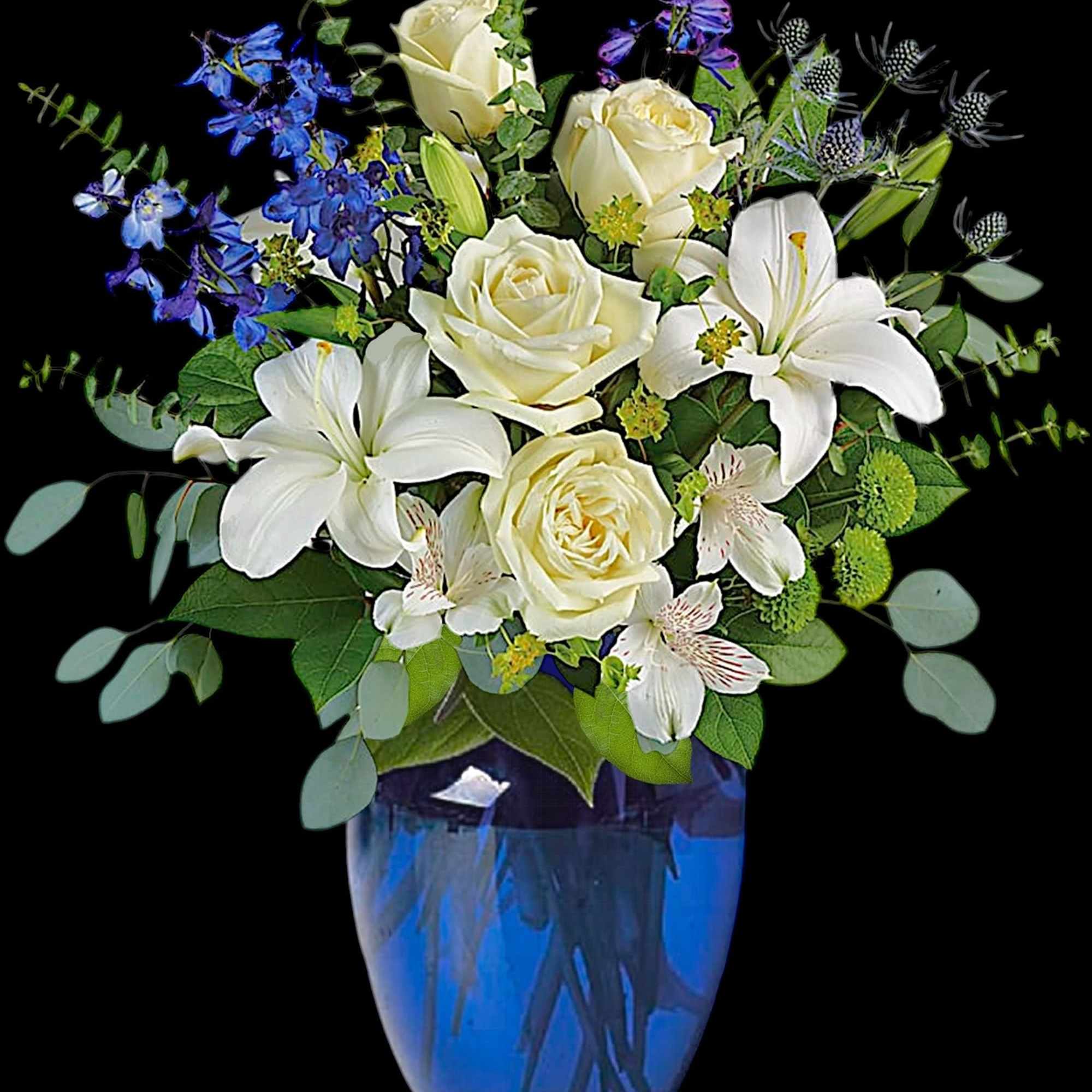 White roses and lilies in a blue glass vase with blue accent flowers
