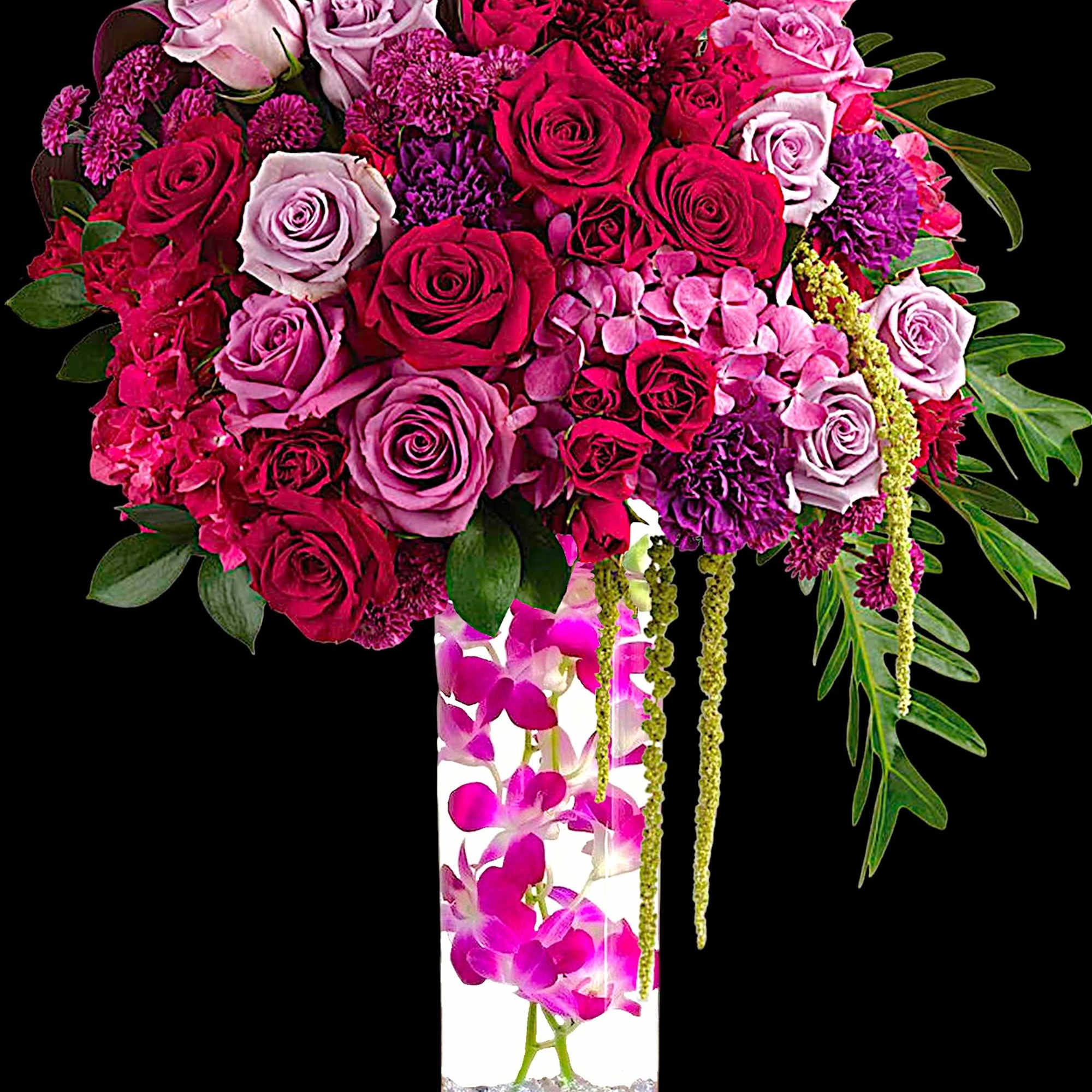 Pink and purple rose arrangement in a tall clear vase with orchids