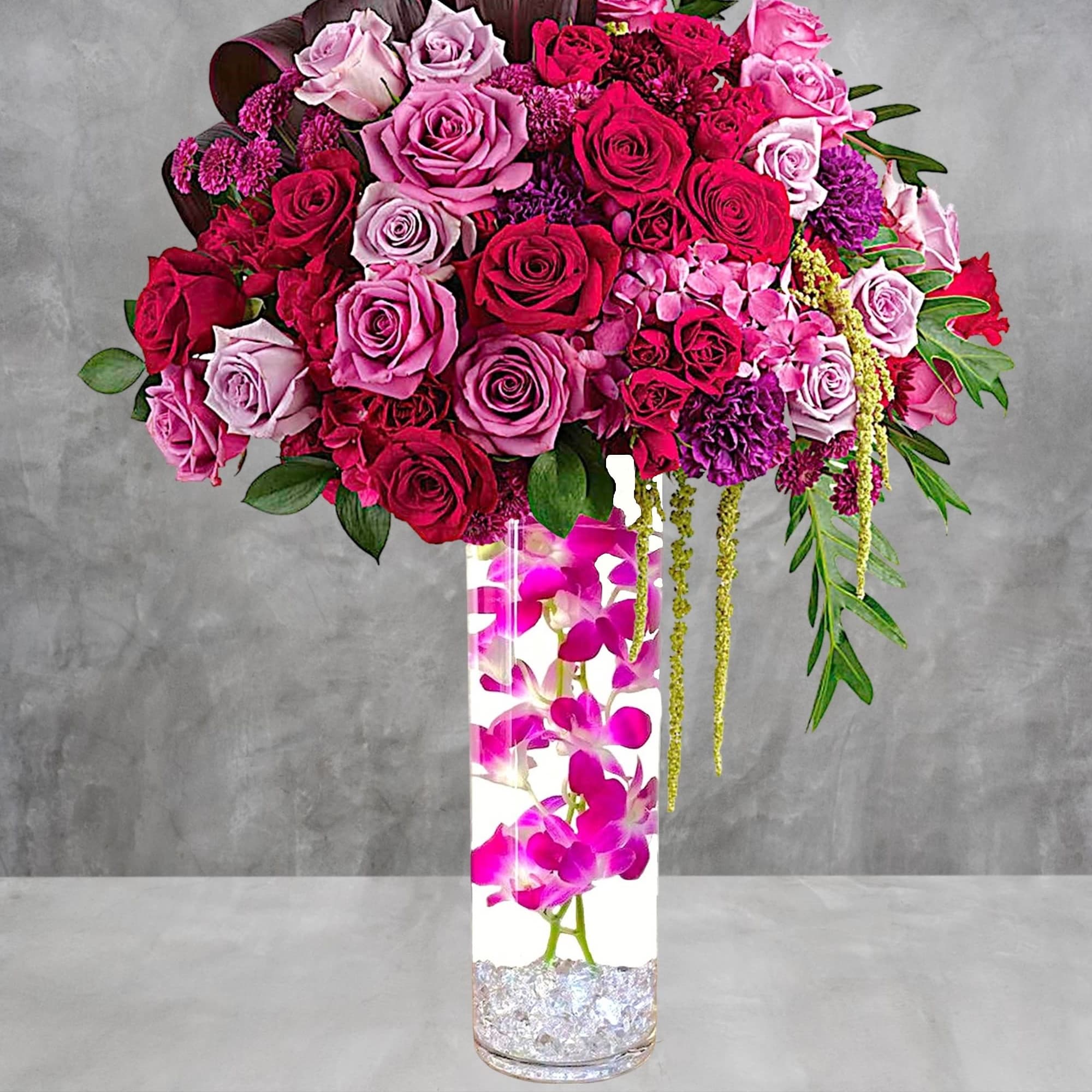 Pink and red rose arrangement in a tall clear vase with orchids, photo 2 of 4
