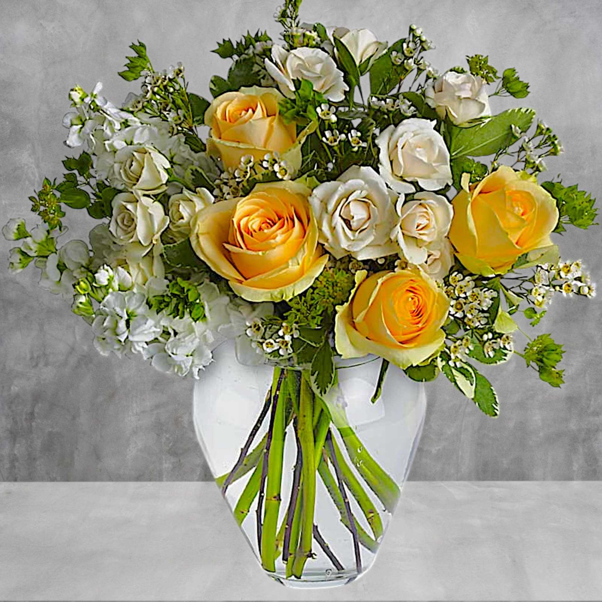 Bouquet of yellow and white roses in a clear glass vase