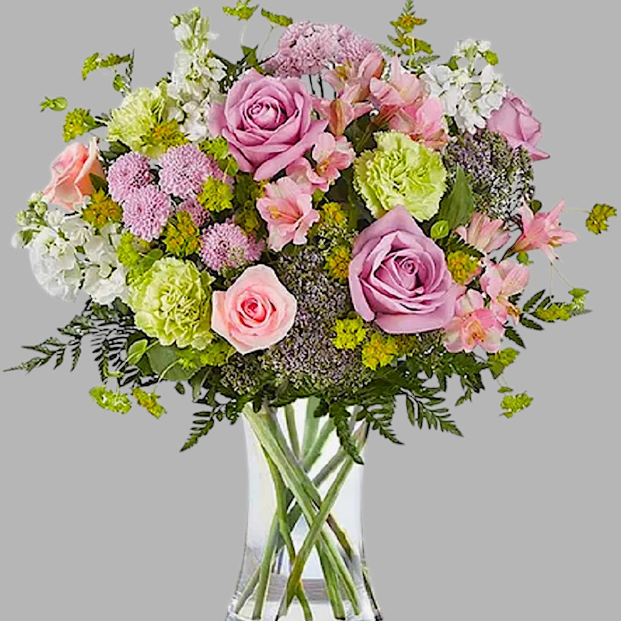 Pink and lavender roses in a clear glass vase with mixed blooms