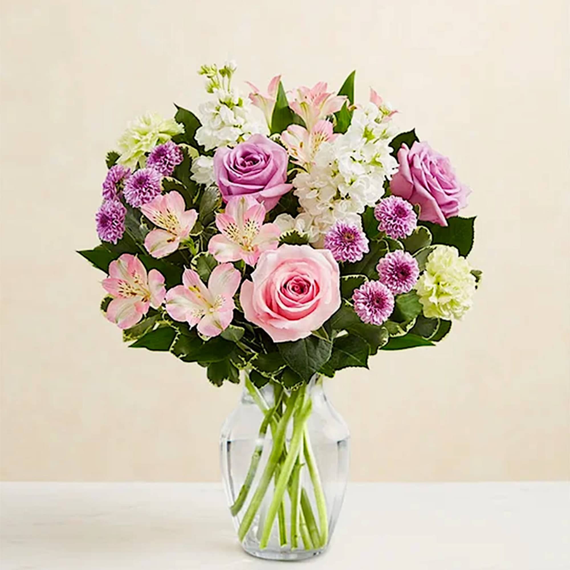Pink roses and mixed flowers arranged in a clear glass vase