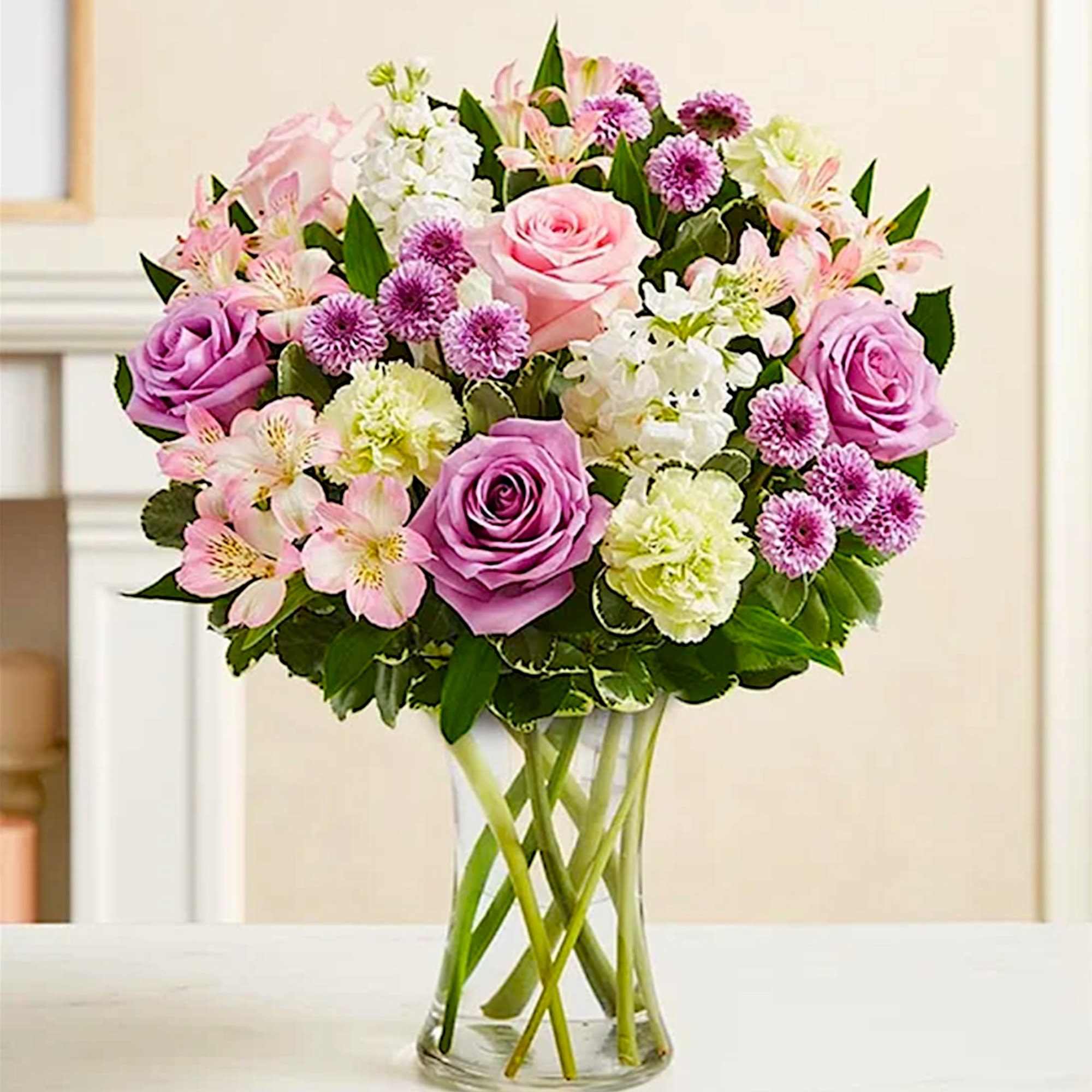 Pink and lavender roses with mixed blooms in a clear glass vase, photo 3 of 6