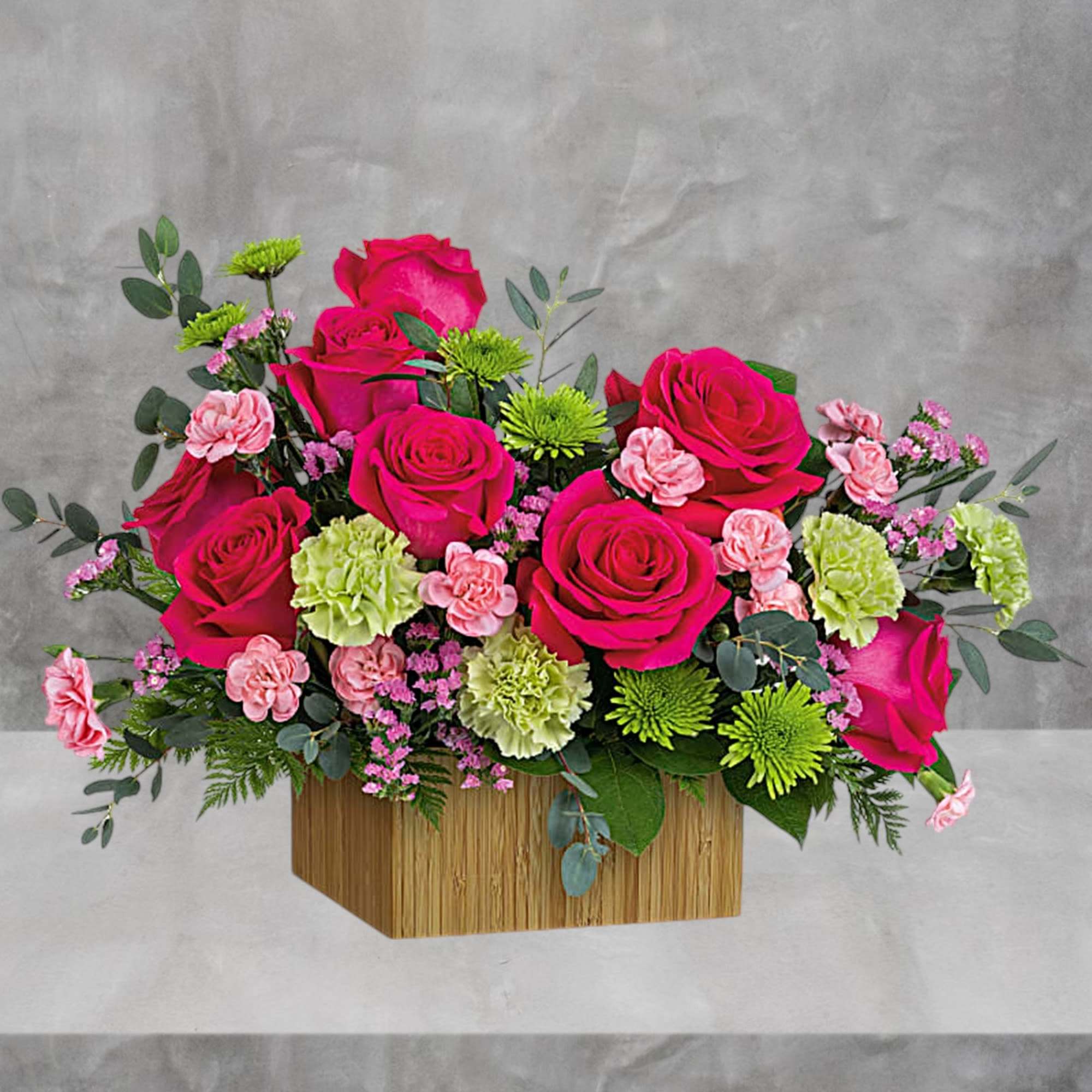 Pink roses and carnations arranged in a wooden box