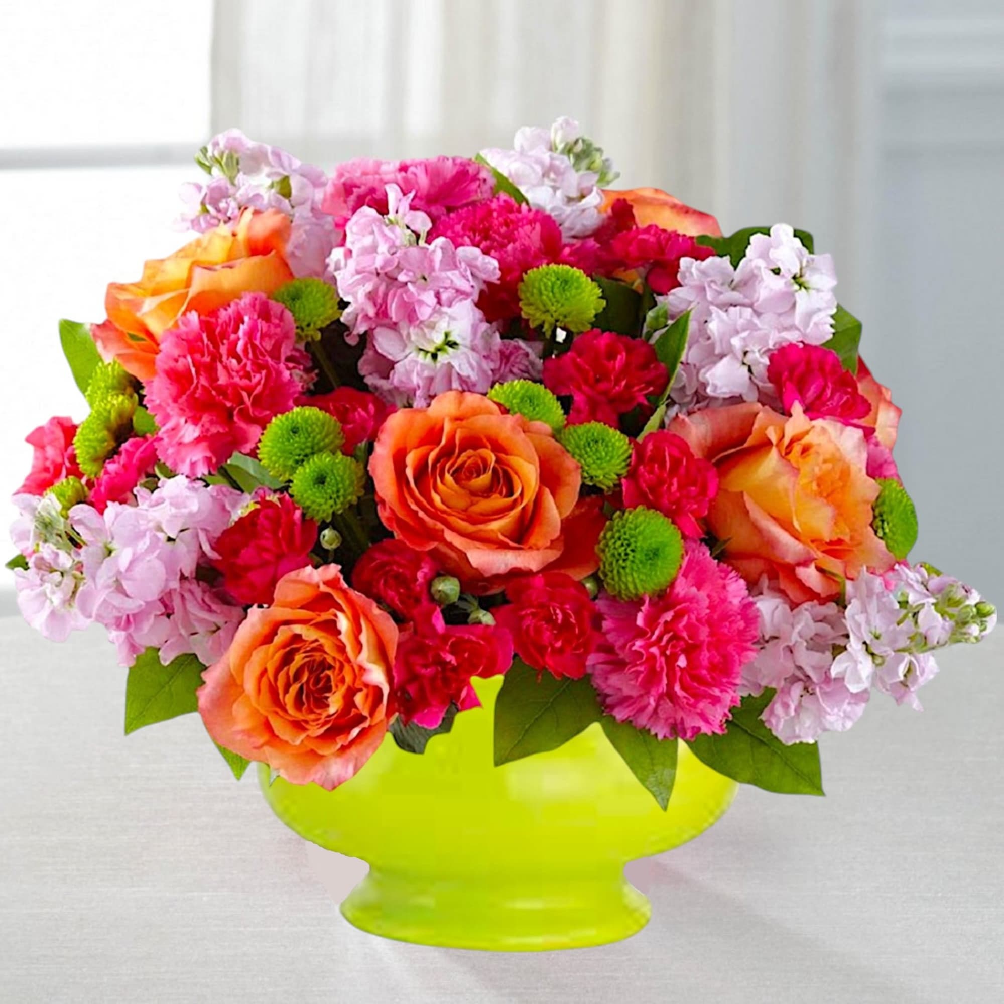 Bright mixed bouquet in a lime green vase with orange roses and pink flowers