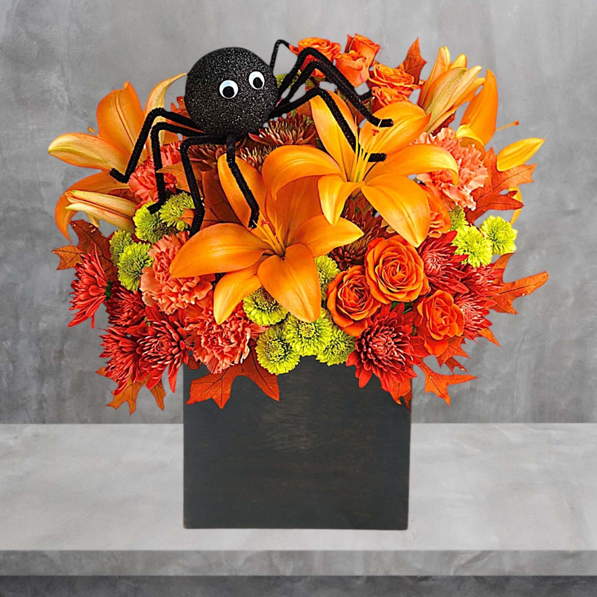 Halloween bouquet with orange lilies and a spider decoration in a black box