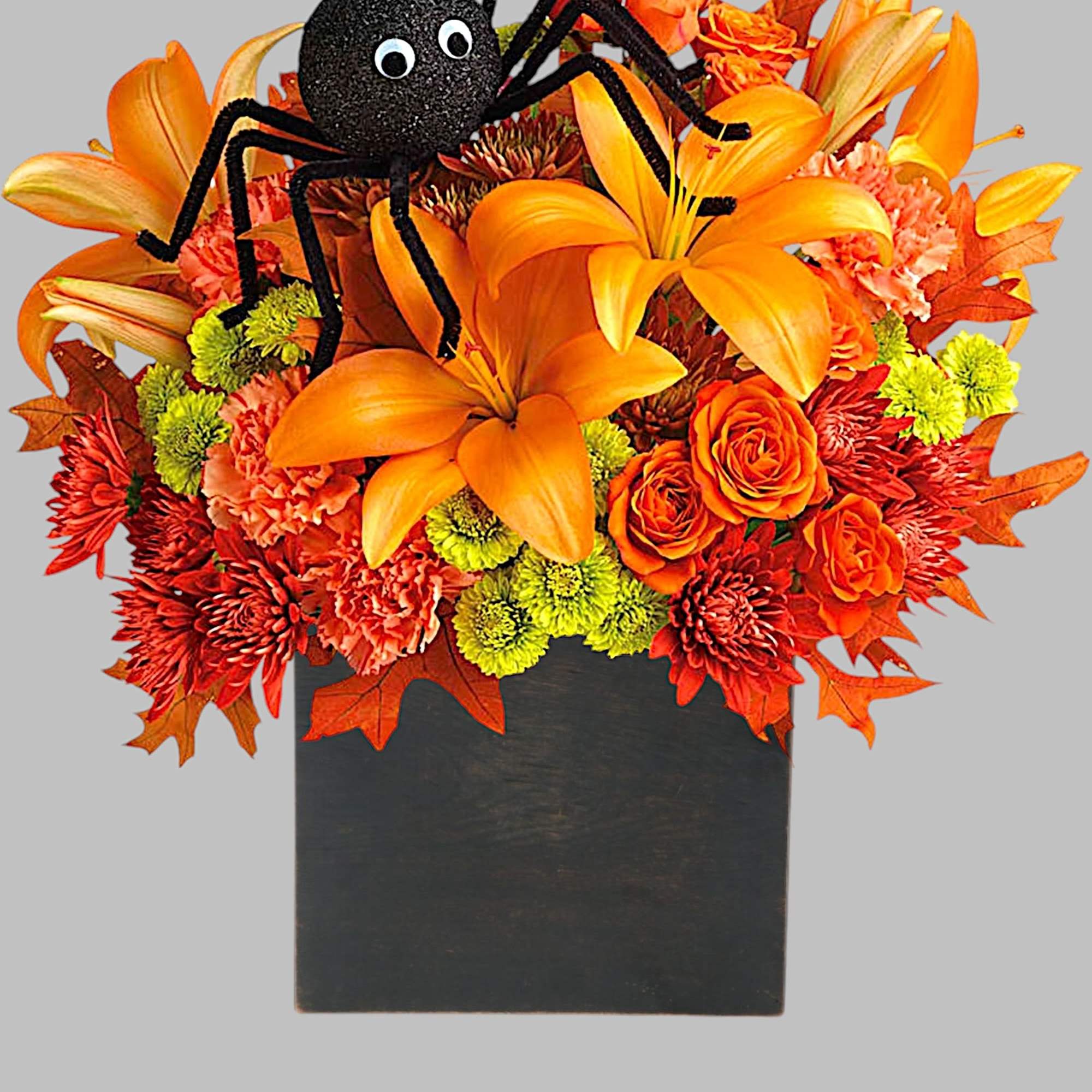 Orange floral arrangement with a black spider decoration in a black container