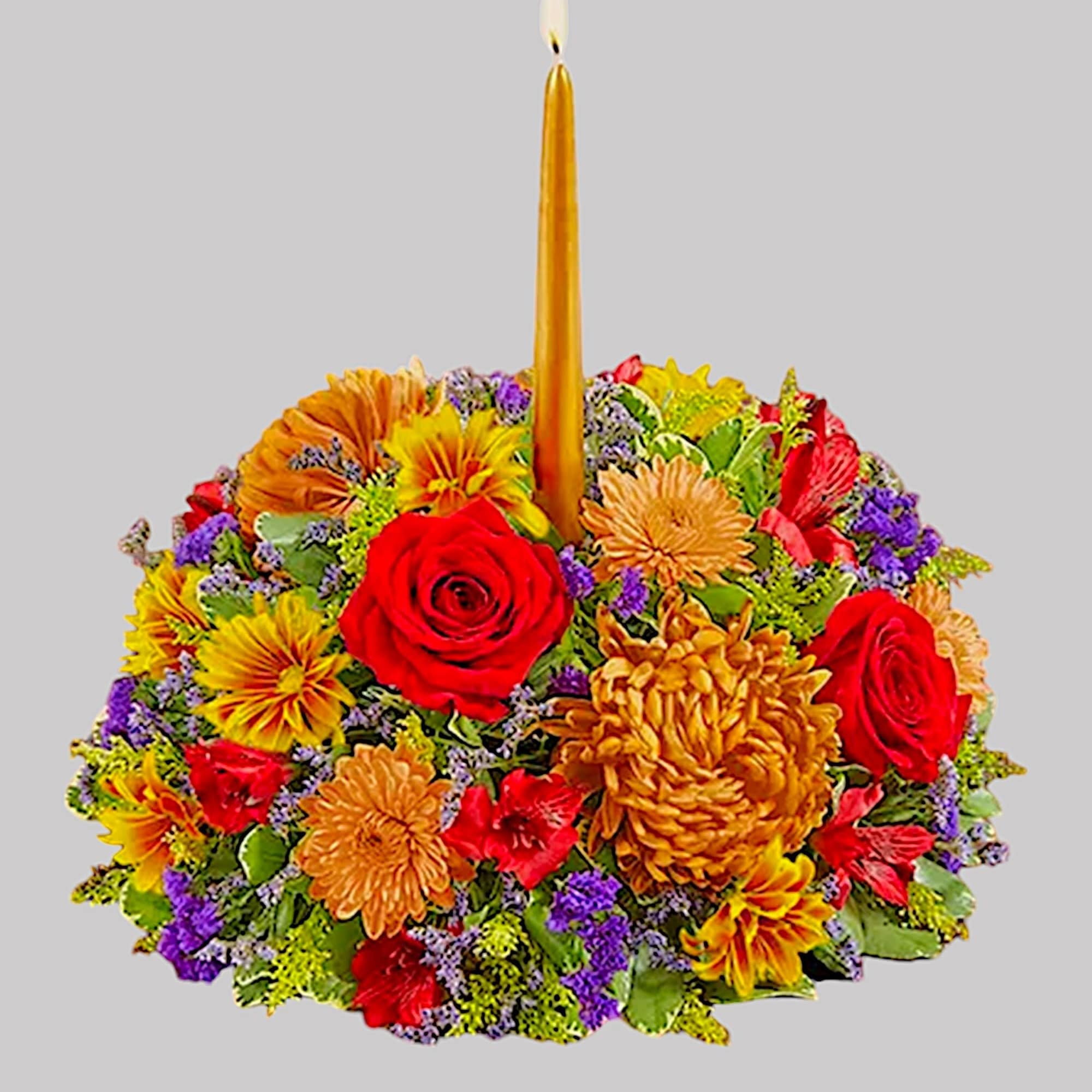 Round floral arrangement with a tall gold candle in the center