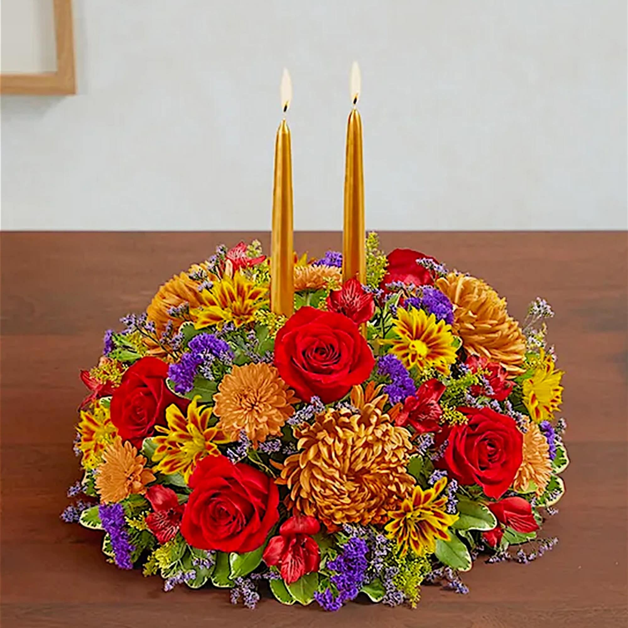 Round floral centerpiece with two gold taper candles