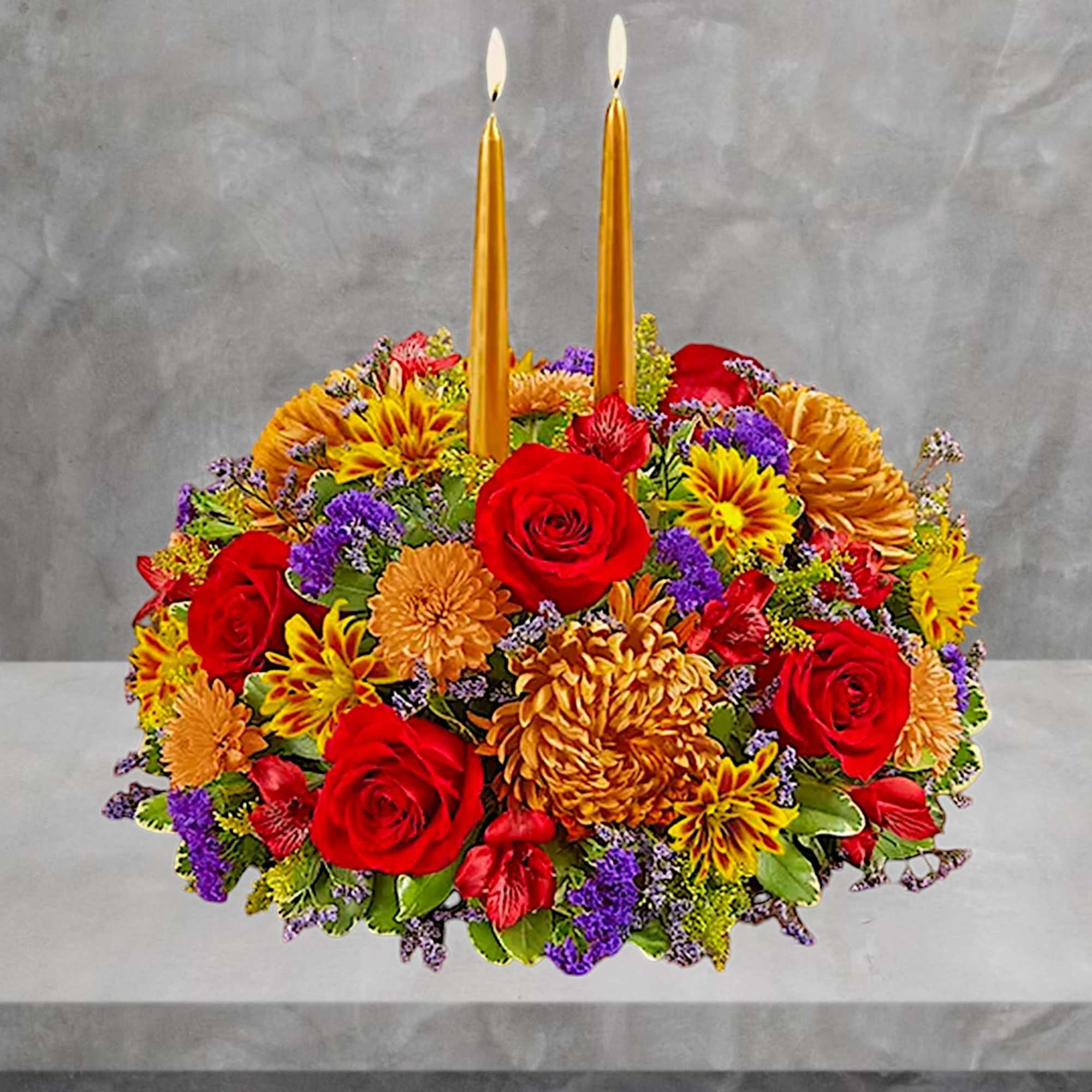 Round floral arrangement with red roses and two gold taper candles