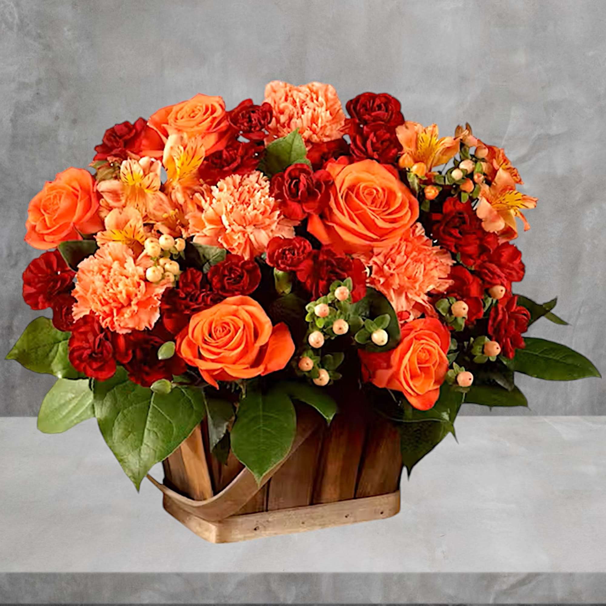 Orange and red floral arrangement in a wooden basket