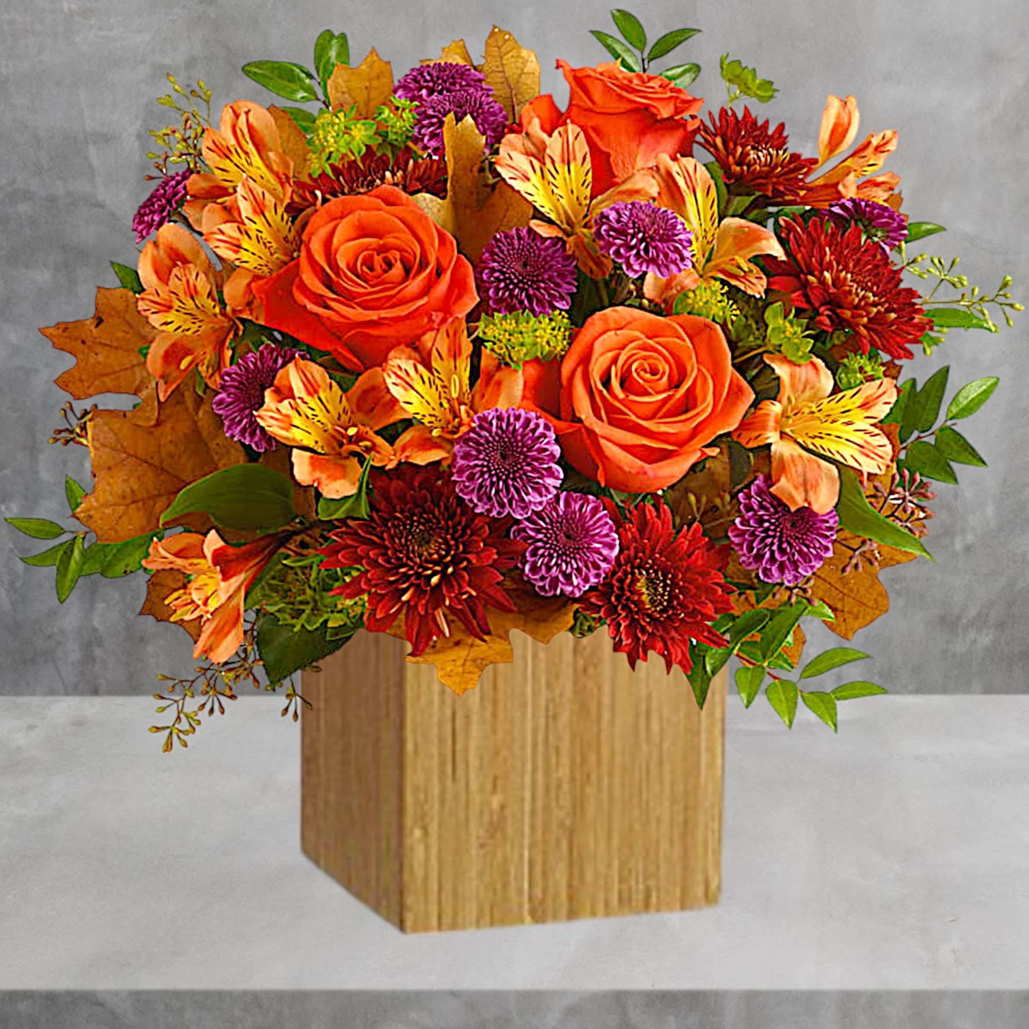 Orange roses and purple chrysanthemums in a wooden cube vase