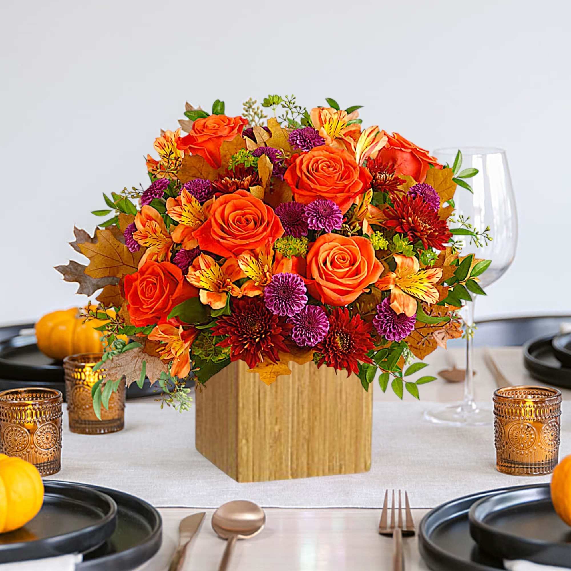 Orange and purple floral centerpiece in a wooden cube vase