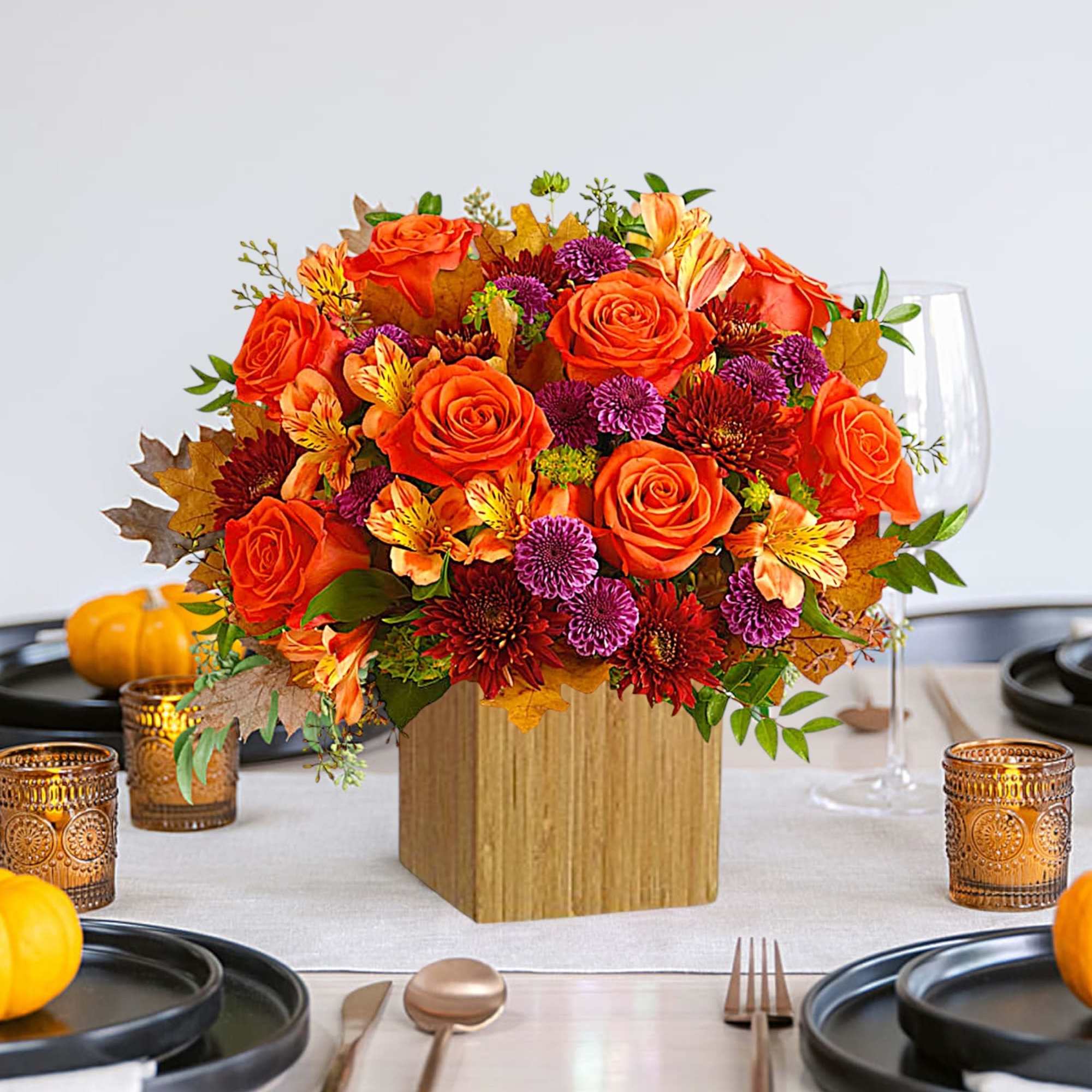 Orange and purple floral centerpiece in a wooden cube vase