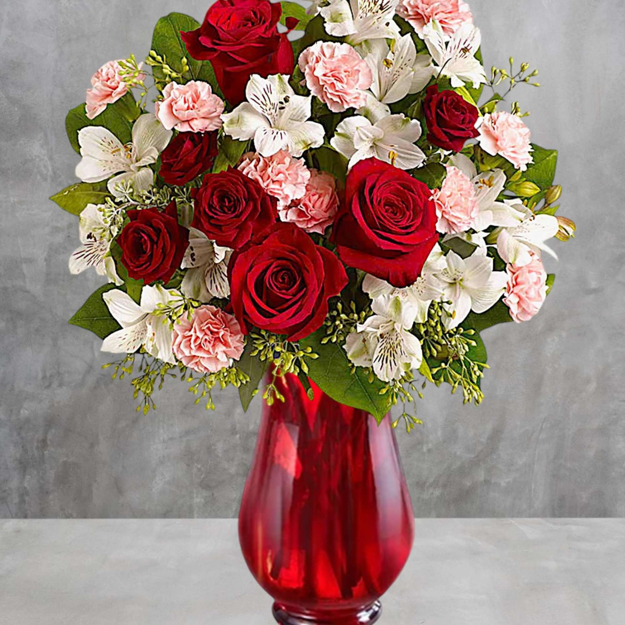 Red roses and white alstroemeria in a red glass vase