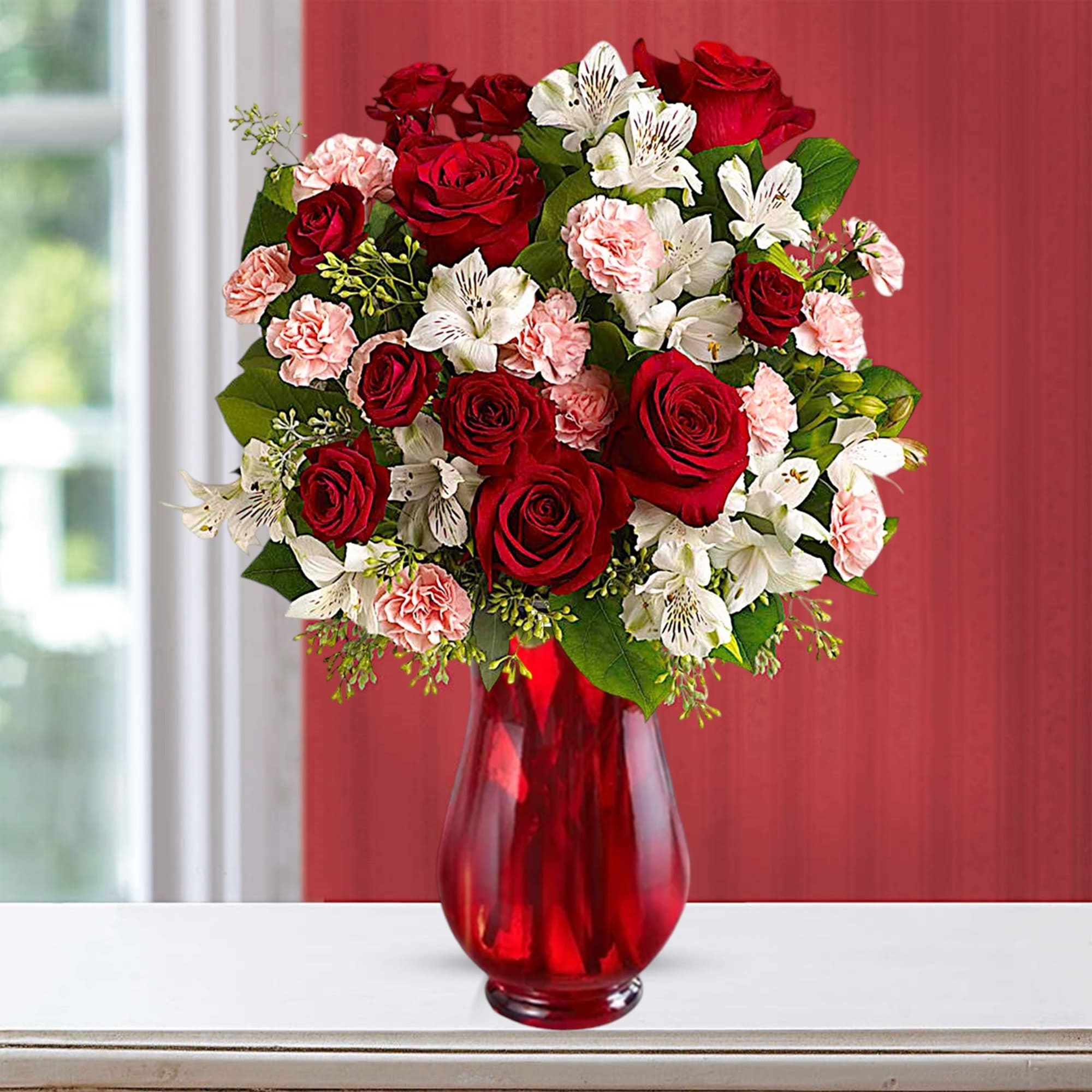 Bouquet of red roses, pink carnations, and white alstroemeria in a red glass vase, photo 2 of 3