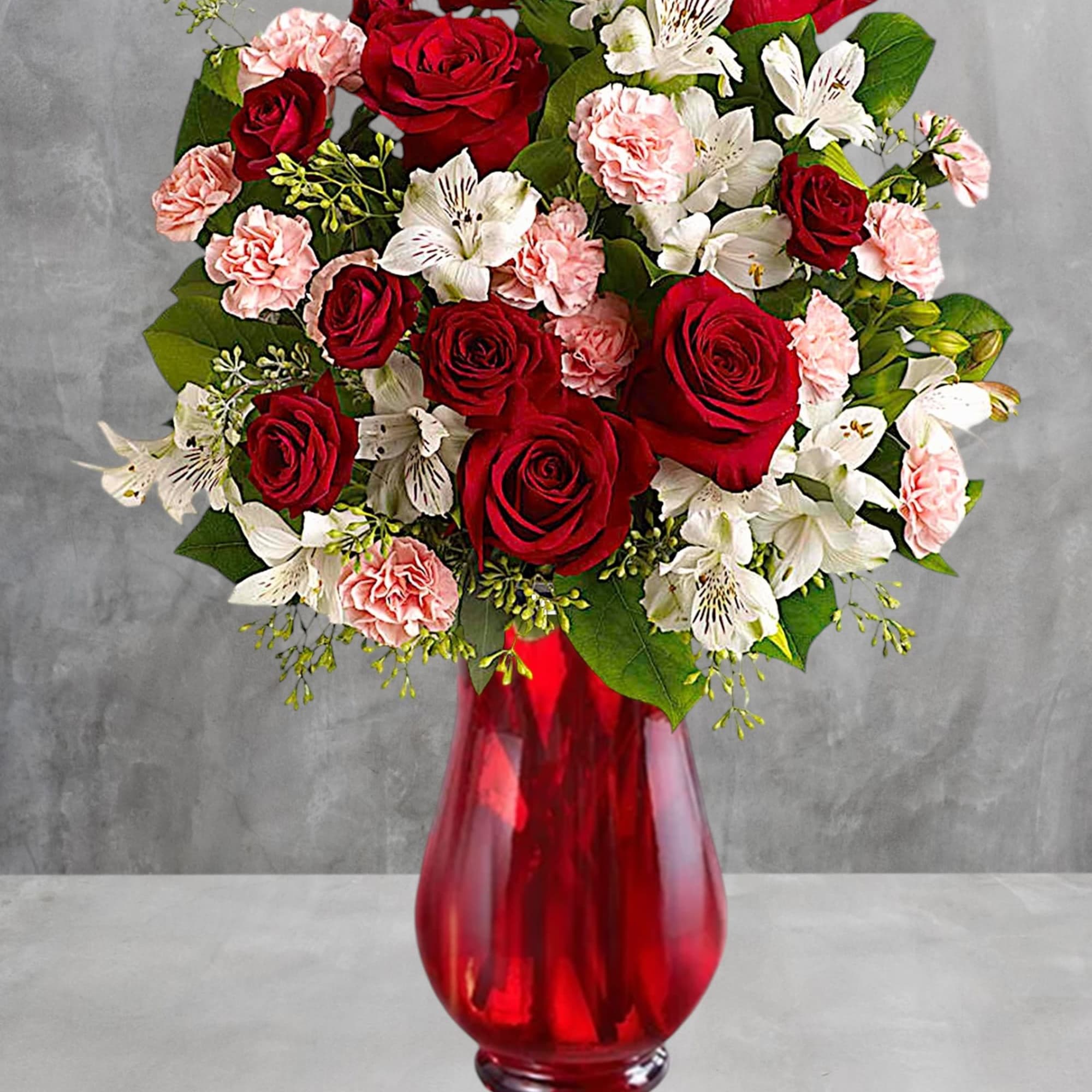 Red roses and white alstroemeria in a red glass vase